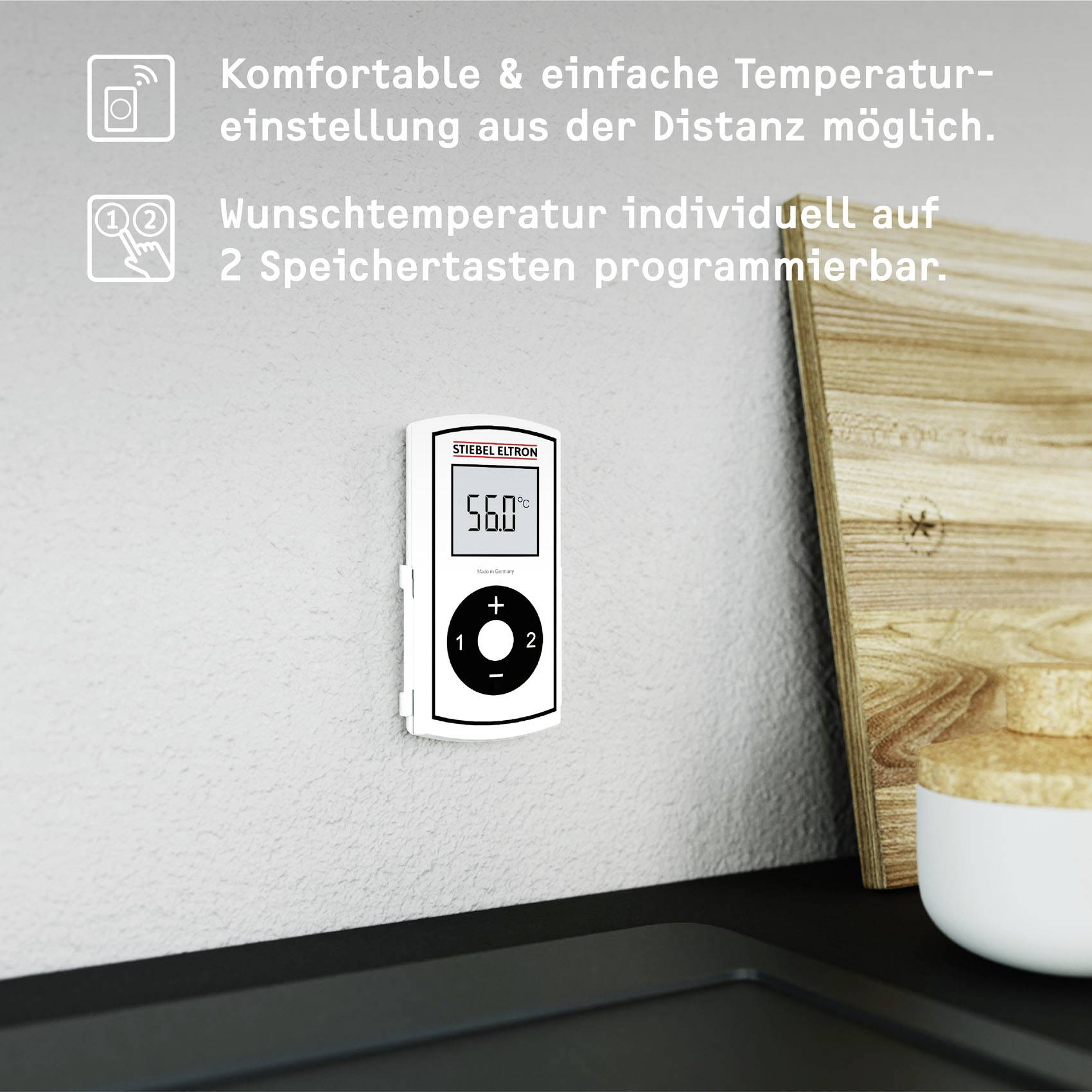 Digitaal thermostaat aan de muur met 'Stiebel Eltron' display. Toont 56°C, knoppen voor temperatuurregeling. Snijplank op de achtergrond.