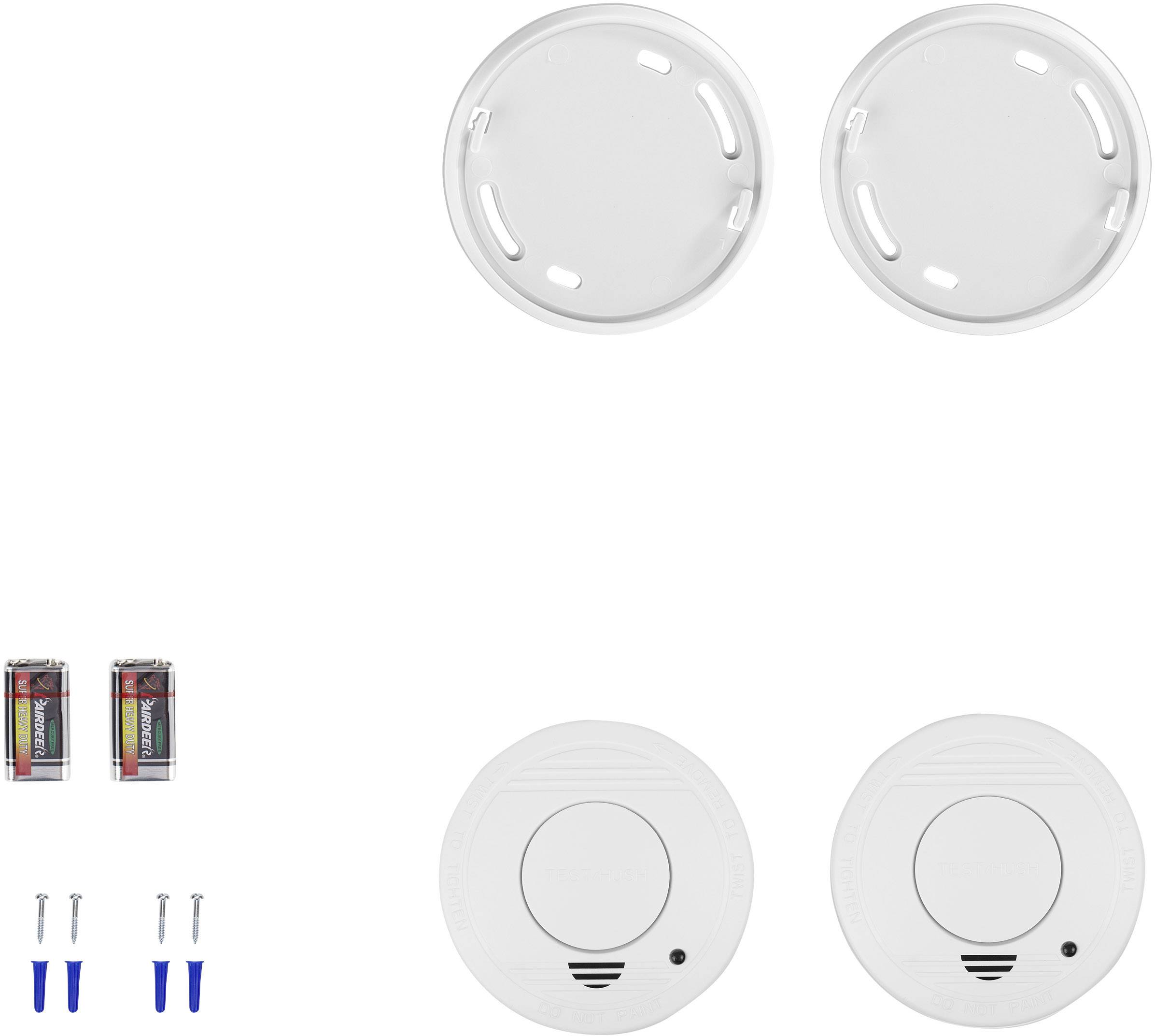Twee witte rookmelders, twee houders, twee batterijen en vier schroeven met pluggen, gerangschikt op een witte achtergrond.