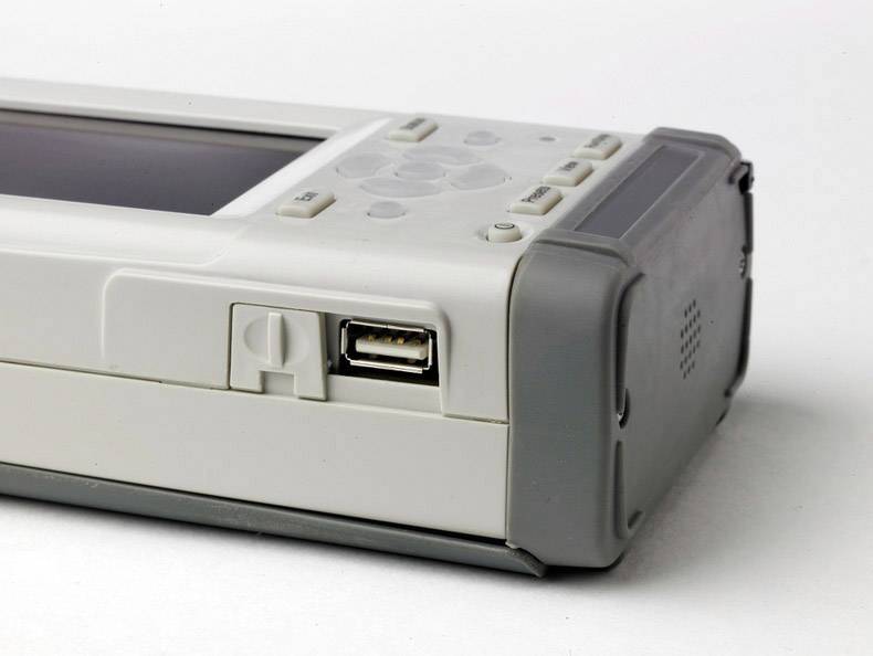 Een wit elektronisch apparaat met grijze randen, meerdere knoppen en een USB-aansluiting aan de linkerkant.