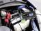Een batterijlader met digitale weergave toont 12,8V, aangesloten op een autobatterij in een voertuigmotorruimte.