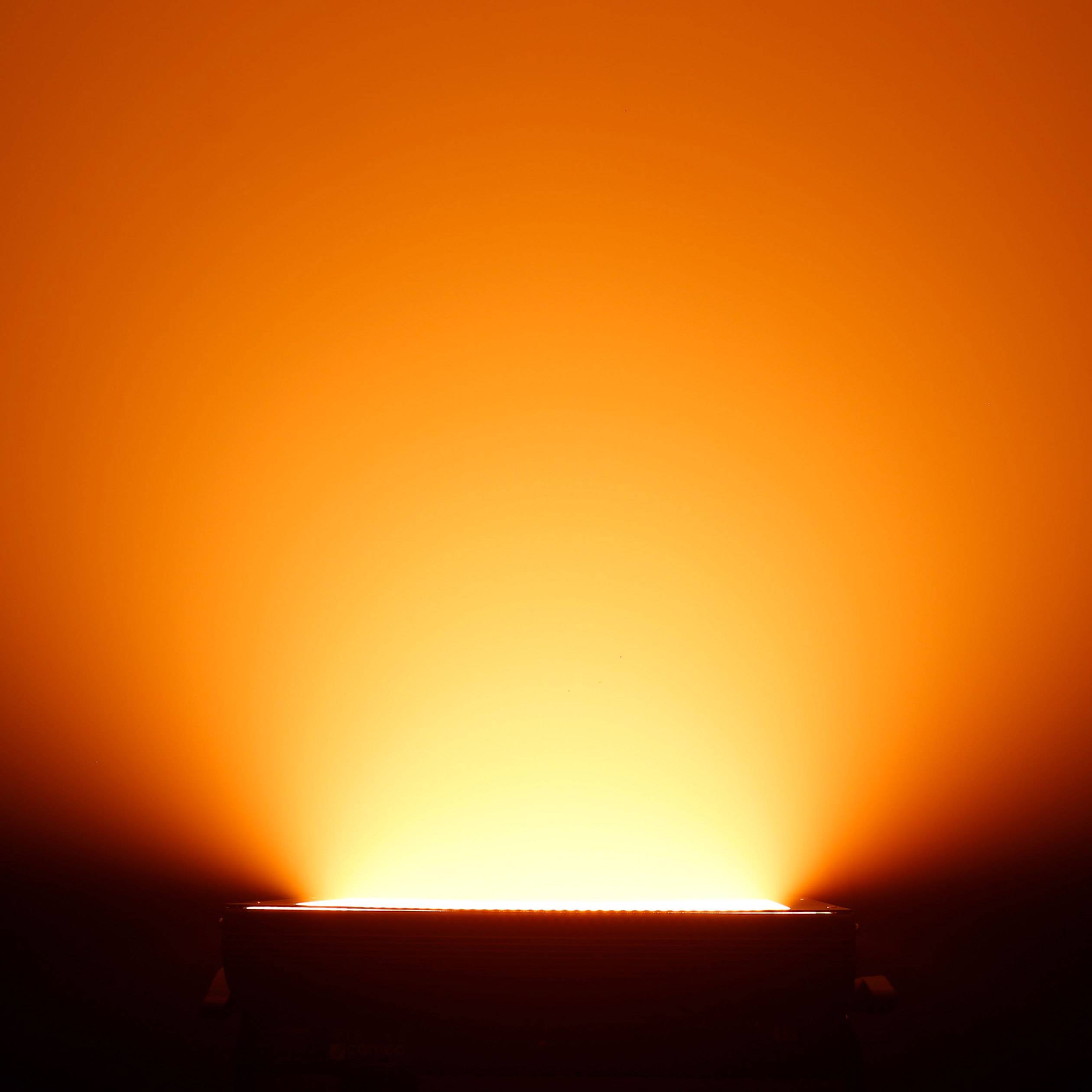 Een helder, oranje licht straalt uit van een lamp en verspreidt warm licht in een donkere ruimte.