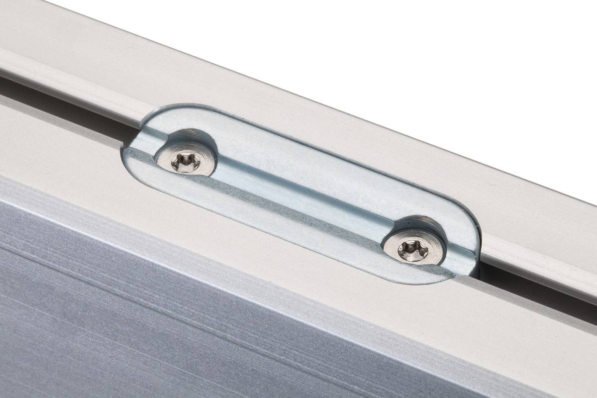 Een metalen verbindingsstuk met twee zichtbare schroeven, gemonteerd op een gladde oppervlakte.