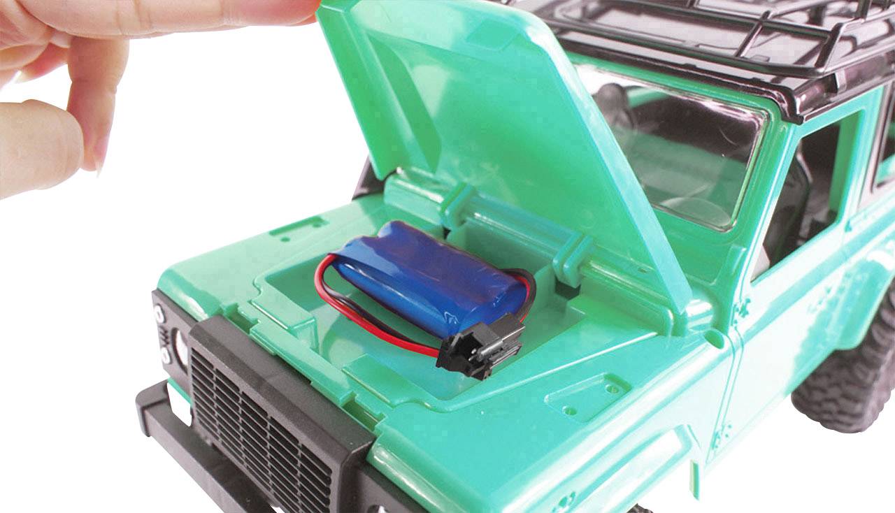 Een hand opent de motorkap van een groene speelgoed-terreinwagen om een blauwe batterij in de motorruimte te tonen.