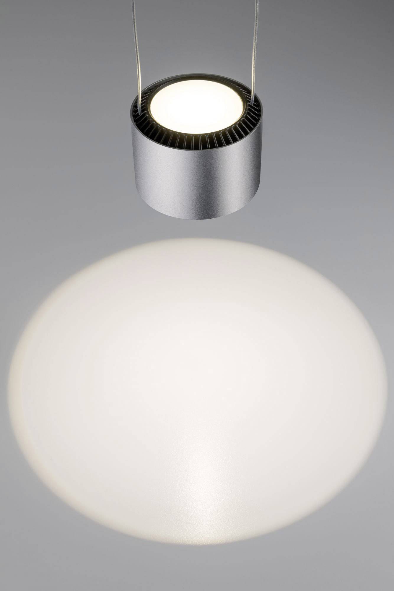 Een ronde hanglamp projecteert een grote, cirkelvormige lichtkring op een grijze oppervlakte.