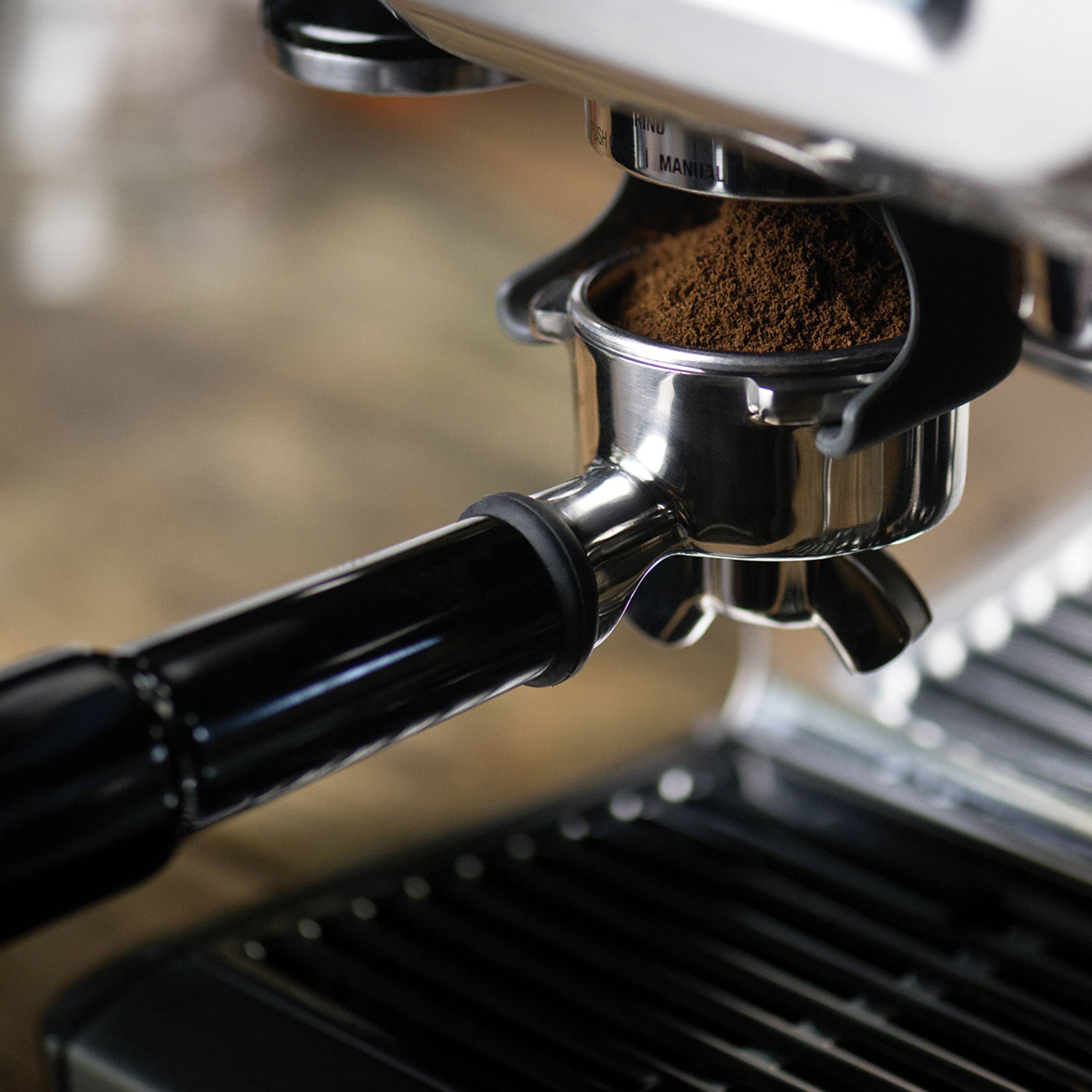 Een espressomachine perst vers gemalen koffie in een filterhouder. De achtergrond is wazig.