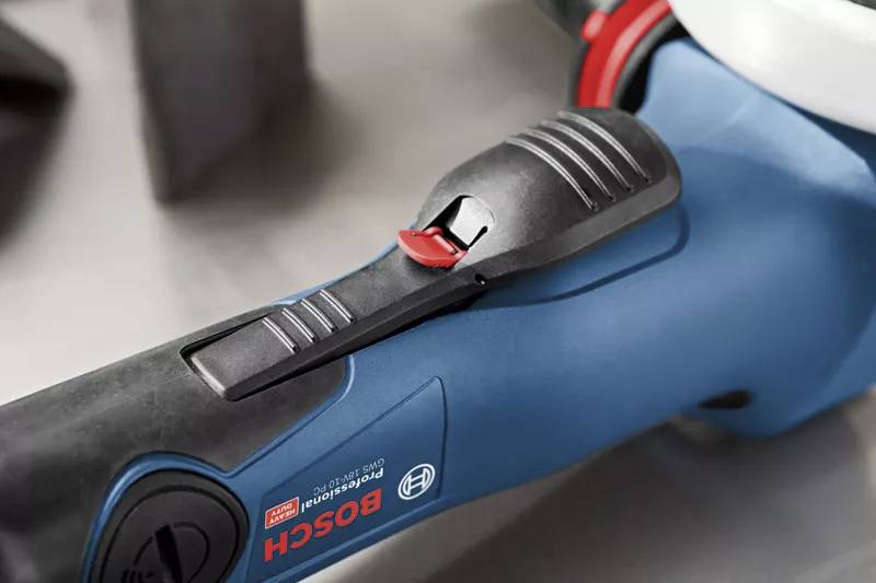 Close-up van een blauw Bosch-gereedschap met een rode schakelaar. De focus ligt op het ergonomische ontwerp van de handgreep.