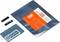 Een bouwpakket bestaande uit een microchip, een blauwe printplaat en een verpakte component met een oranje etiket.