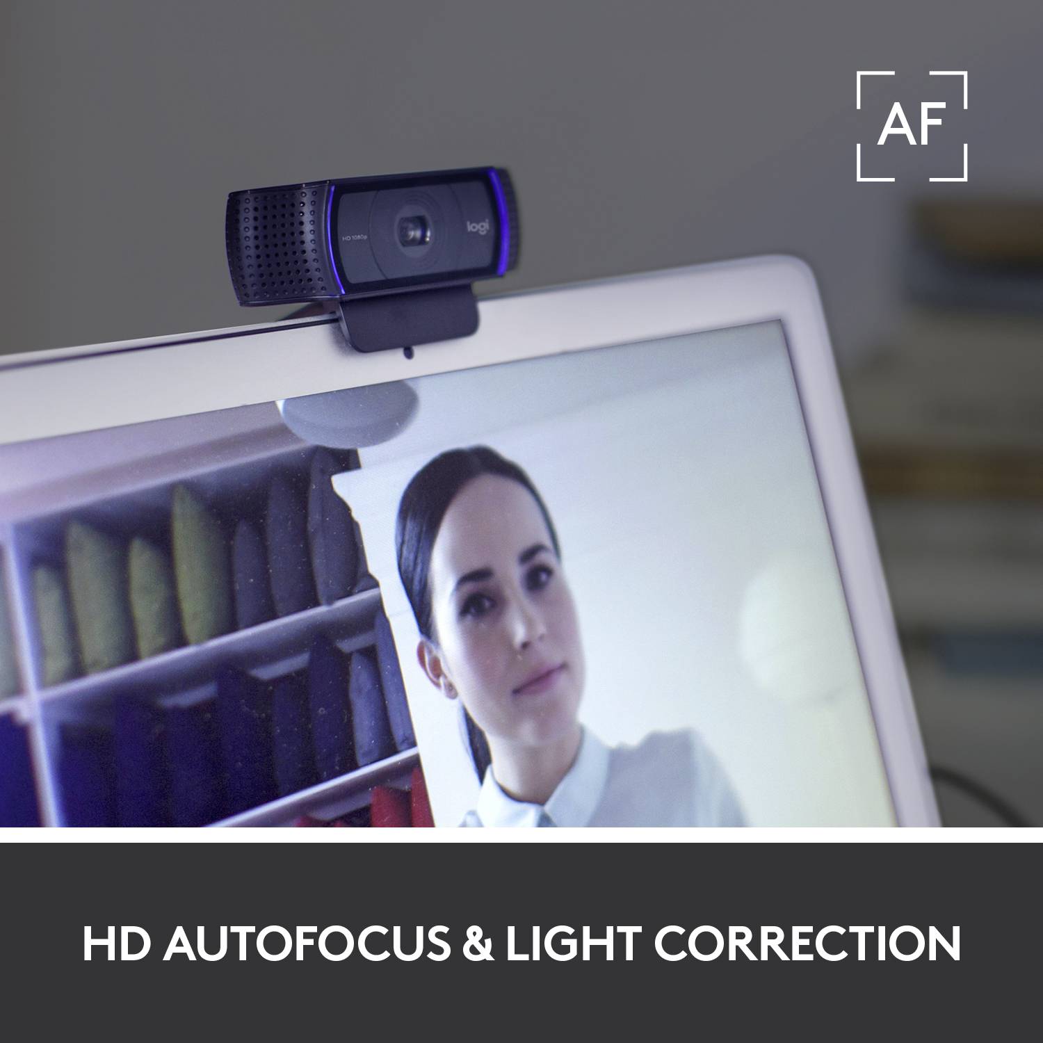 Logitech-webcam op een monitor, toont een persoon op het scherm en tekst onderaan: 'HD-autofocus en belichting correctie'.
