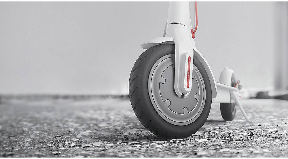 Close-up van het voorwiel van een elektrische step op asfalt. De step is modern en wit. De afbeelding benadrukt de stabiliteit en stedelijke toepassing.