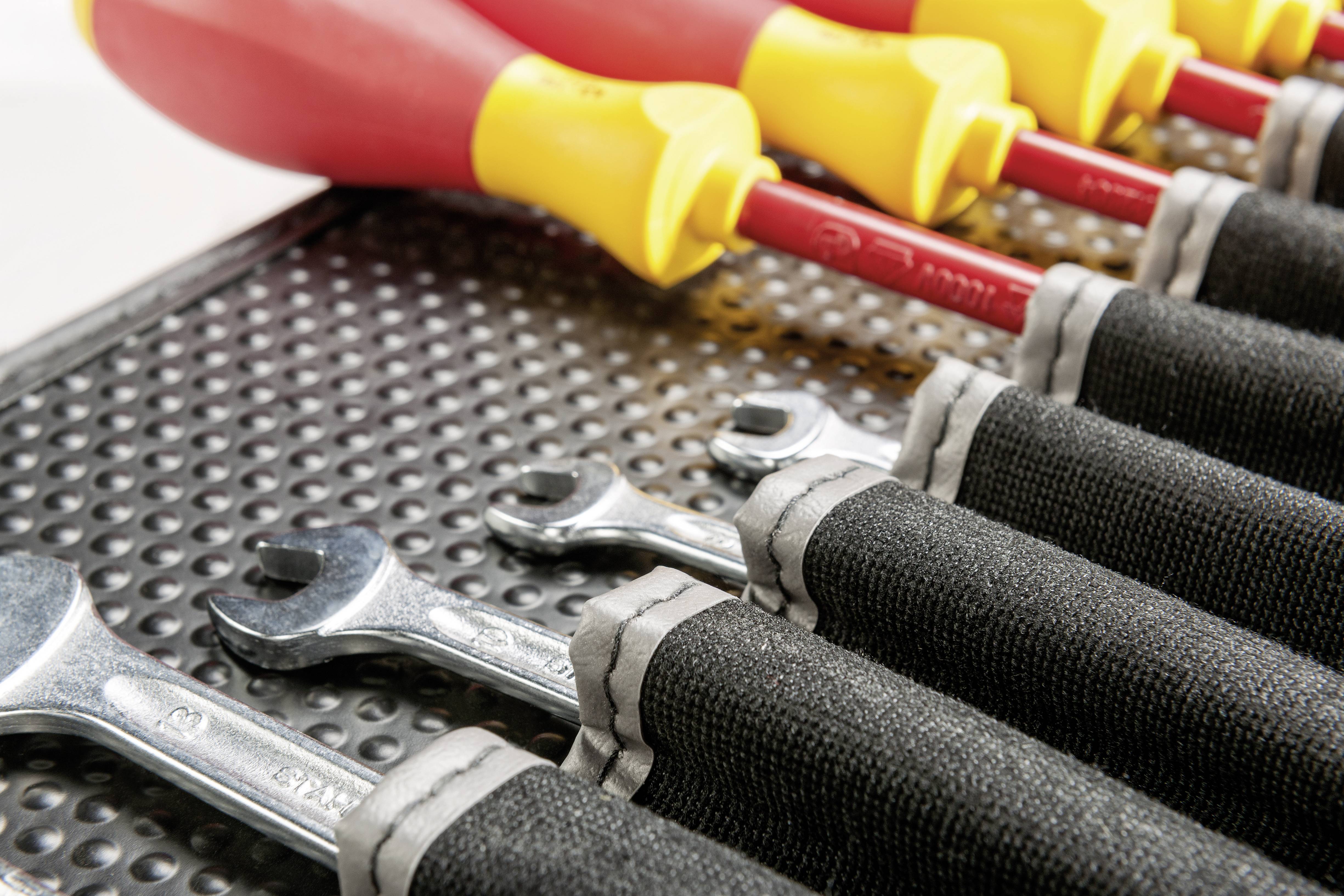 'Close-up van schroevendraaiers met rode handgrepen en open ringsleutels, netjes gerangschikt op een metalen ondergrond.'