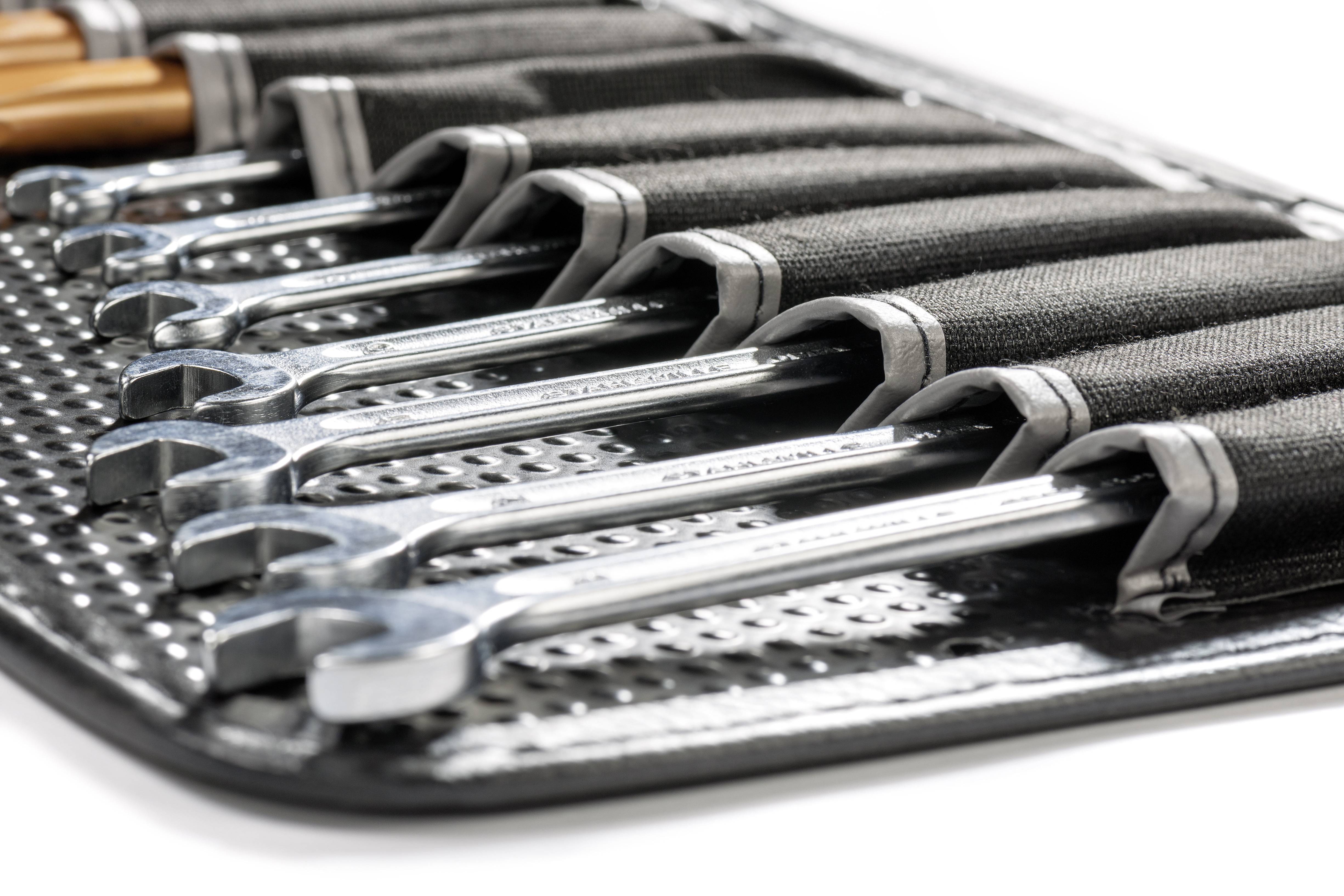 Een set glanzende moersleutels in een zwarte stoffen tas, netjes gerangschikt en klaar voor gebruik.