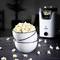 Kom met verse popcorn staat op een tafel, met op de achtergrond een popcornmachine.