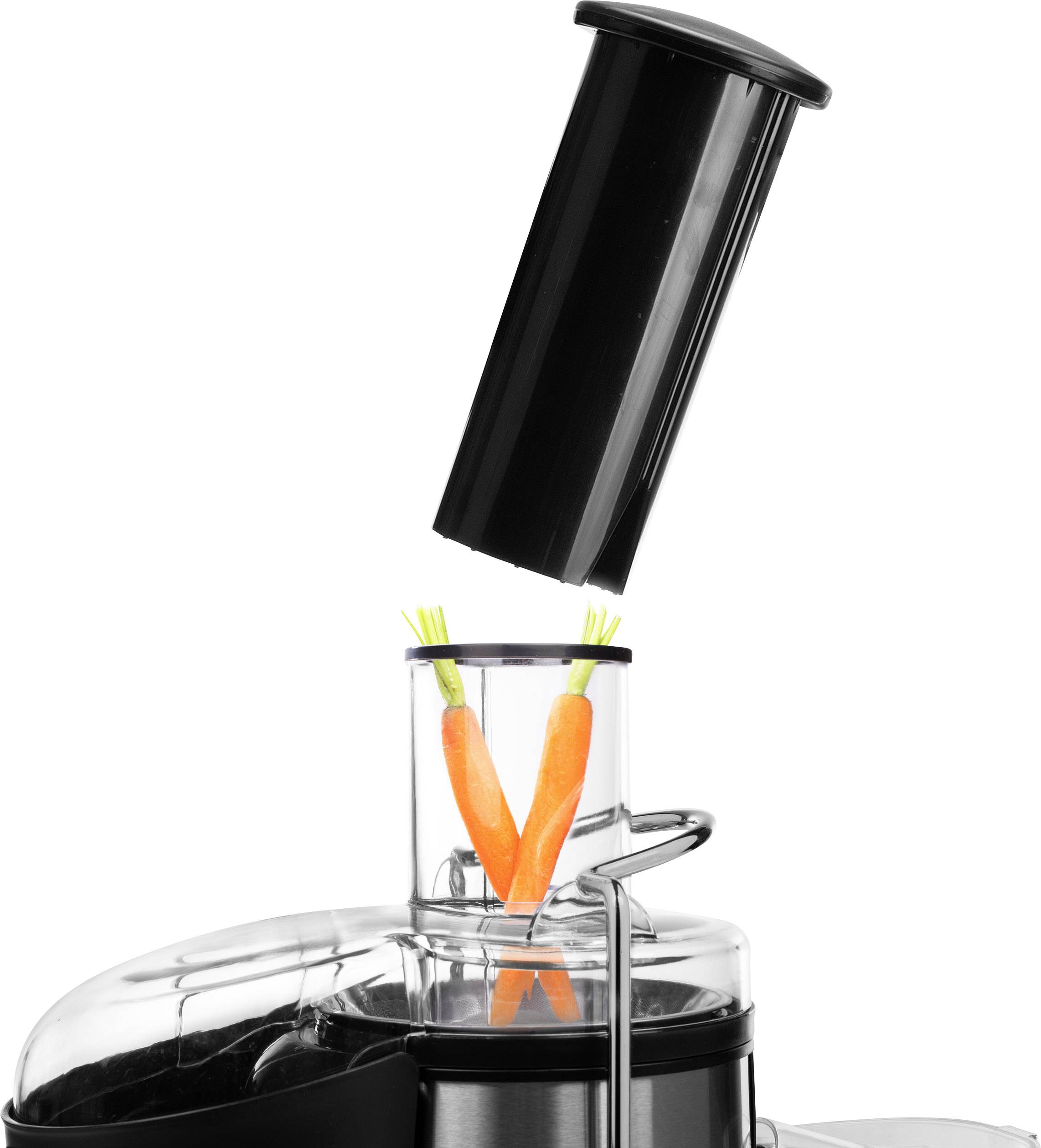 Sapcentrifuge: Twee wortels worden in de invoerbuis van een zilver en zwart sap-apparaat gedaan.