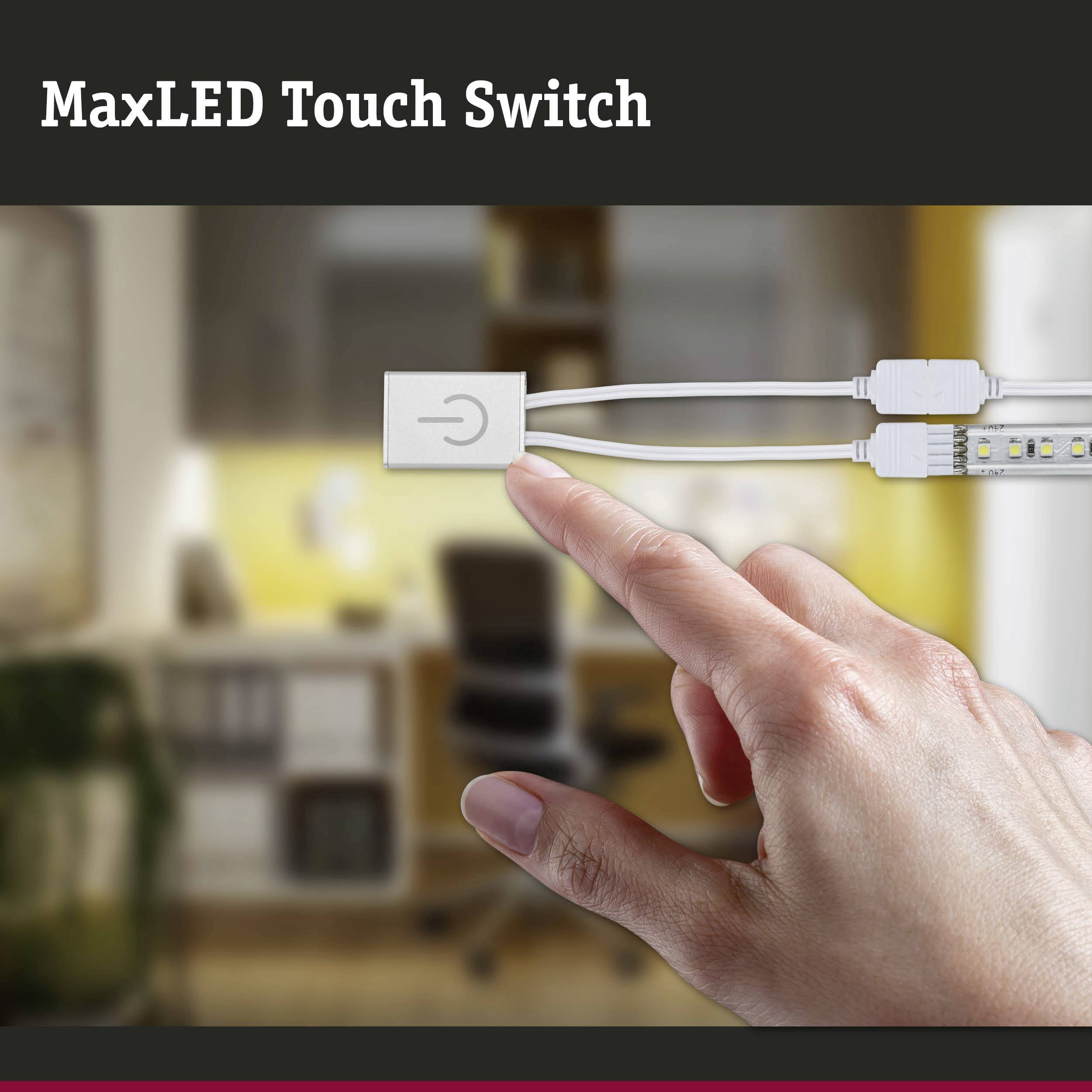 Een hand nadert een 'MaxLED Touch Switch' voor een onscherpe achtergrond die een keuken toont.