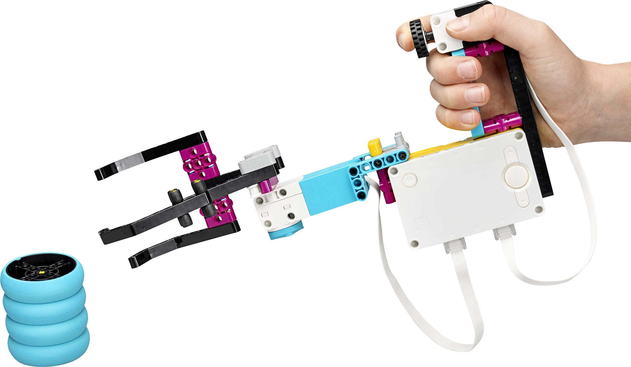 Een hand houdt een Lego-robotarm vast die gericht is op het grijpen van drie bovenop elkaar gestapelde blauwe ringen.