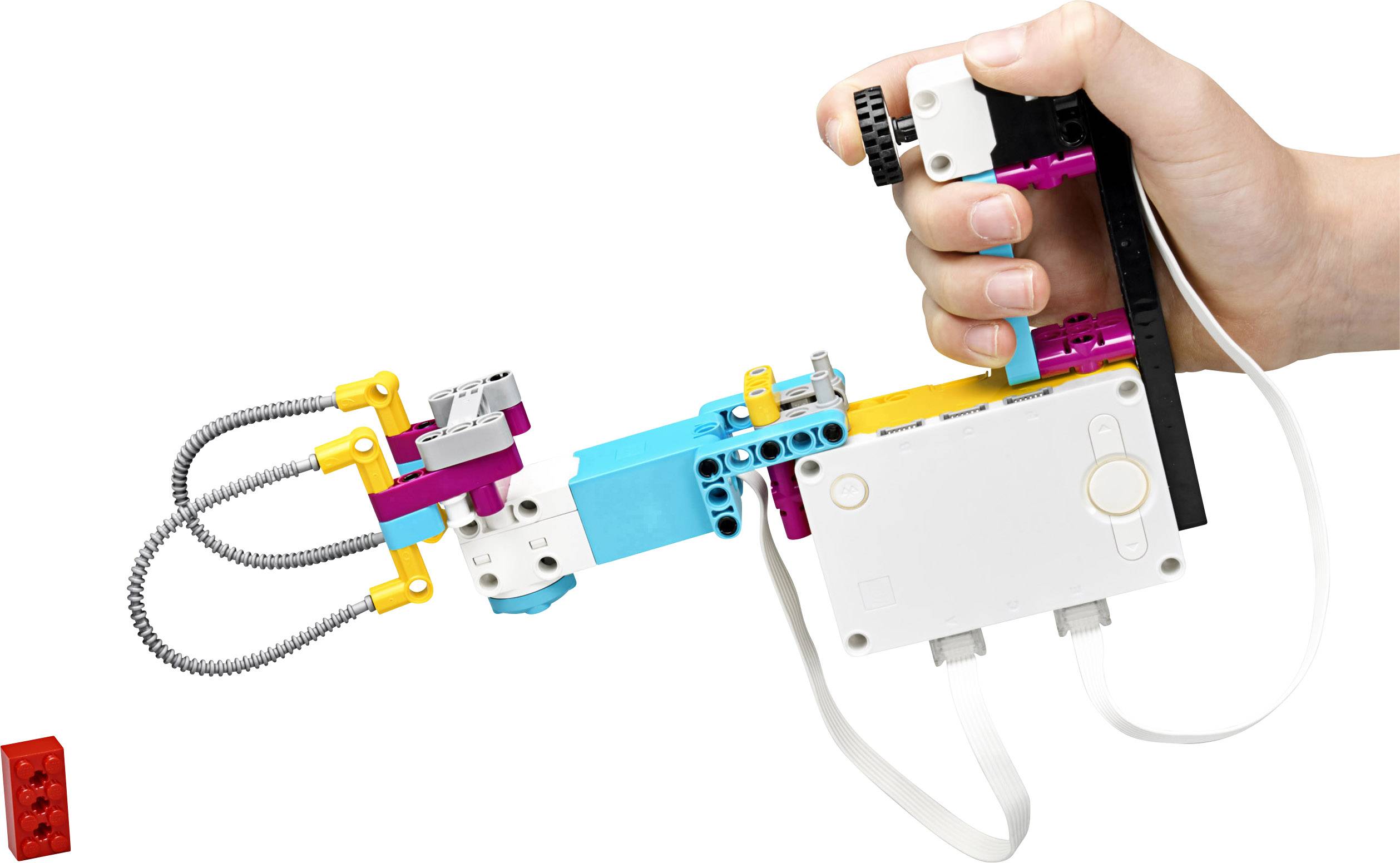 Een hand houdt een kleurrijk, technisch LEGO-model met kabels vast, dat een grijphand voorstelt en onderdelen beweegt.