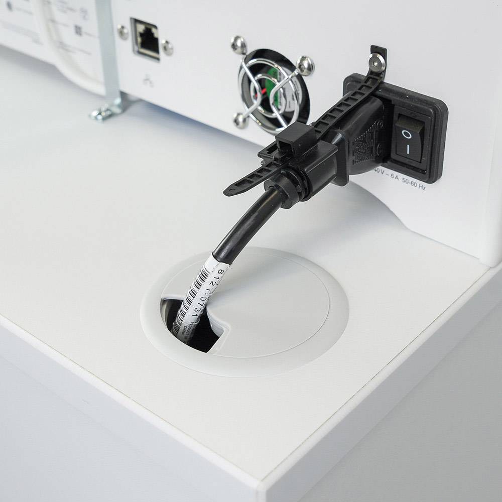 Een stroomkabel die in de achterkant van een elektronisch apparaat wordt gestoken. Naast de kabel bevindt zich een netschakelaar.