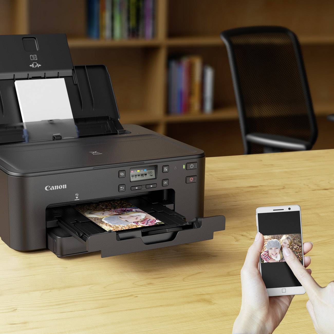Multifunctionele printer print een foto af; persoon gebruikt een smartphone voor draadloze besturing. Op de achtergrond een boekenplank.