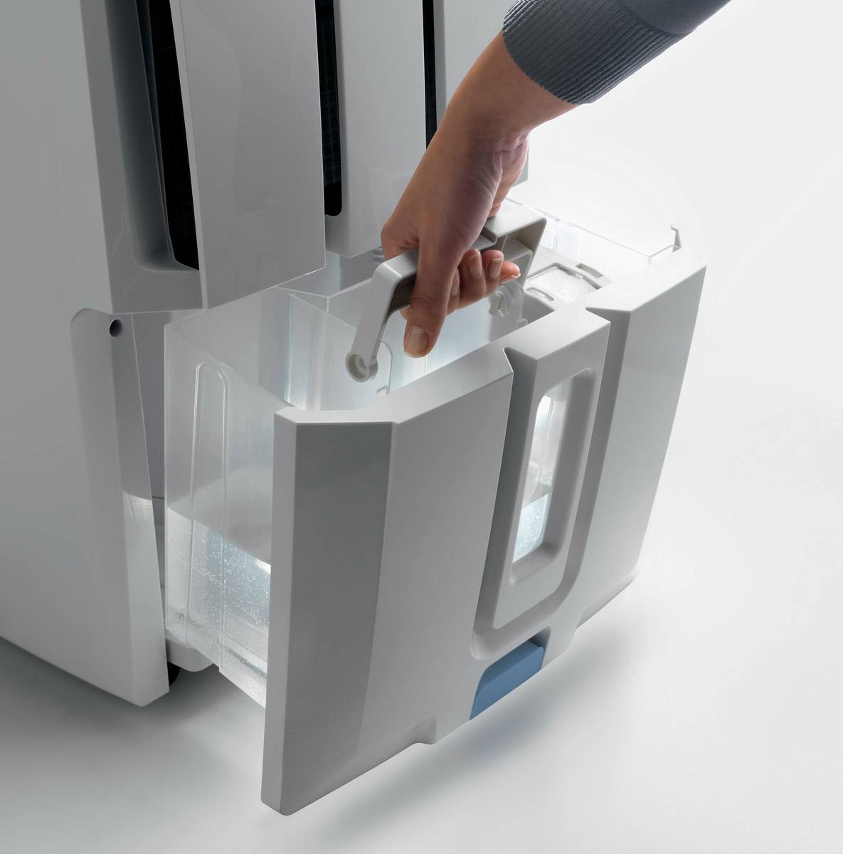 Een hand trekt de watercontainer uit een witte luchtontvochtigaar. De container heeft een handgreep voor gemakkelijk verwijderen.