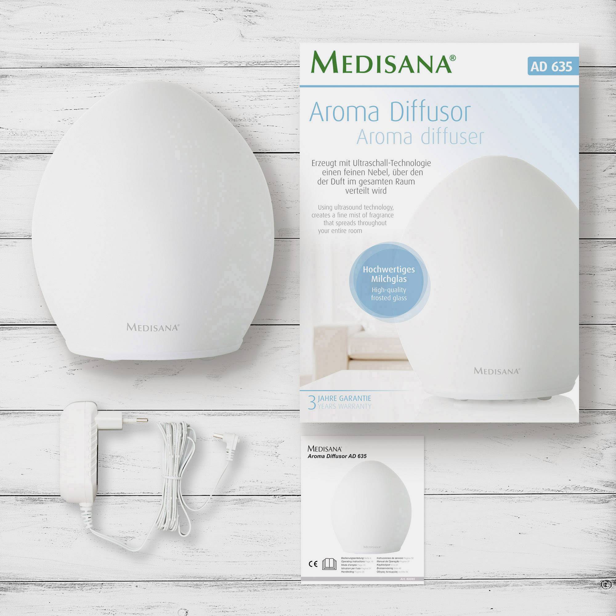 De Medisana Aroma-diffuser AD 635 voor een houten oppervlak, naast hem de verpakking en kabel. Bevordert aromatherapie in de ruimte.