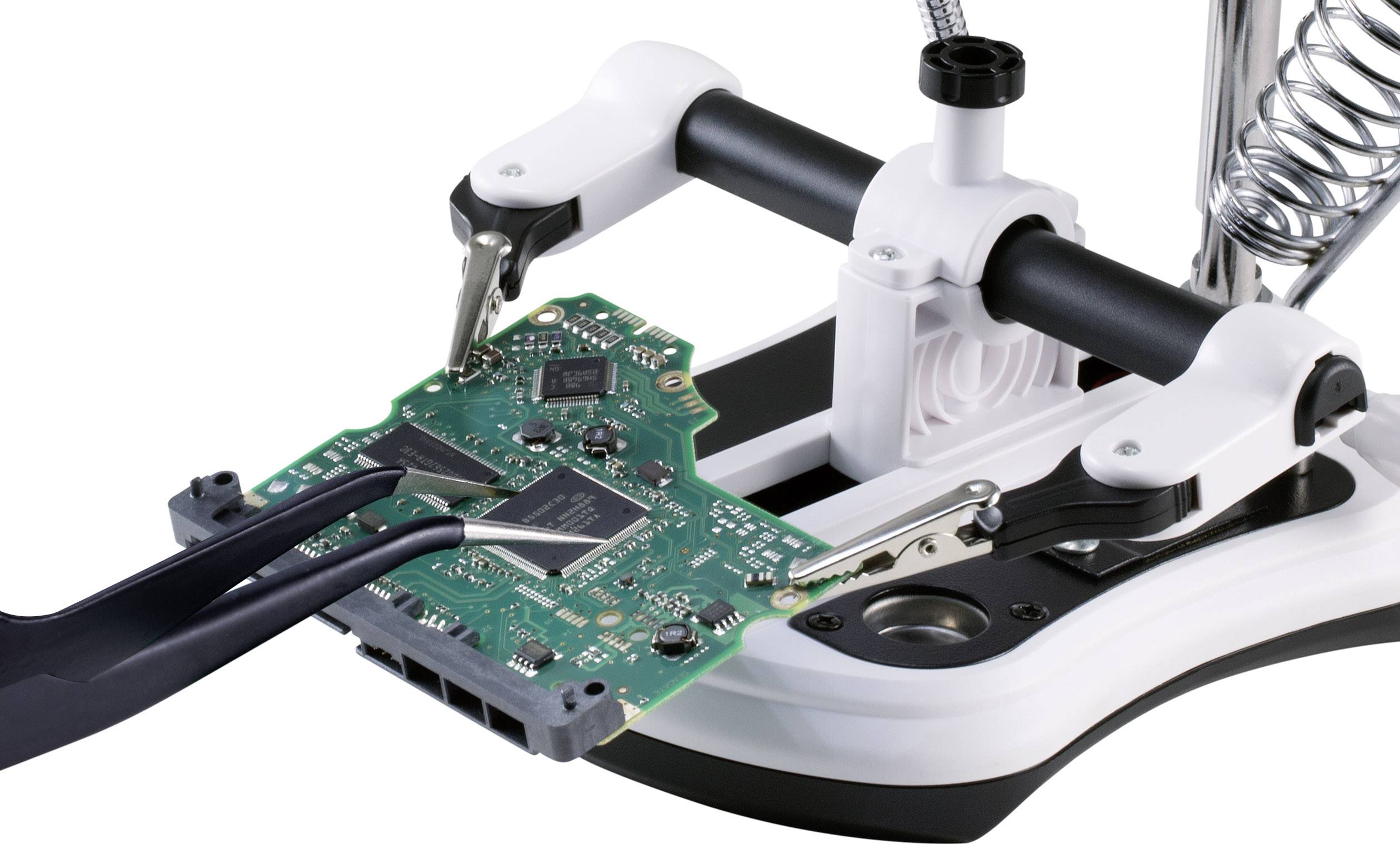 Een printplaat wordt met een klem vastgezet, terwijl een tang een chip vasthoudt om precisiewerk te vergemakkelijken.