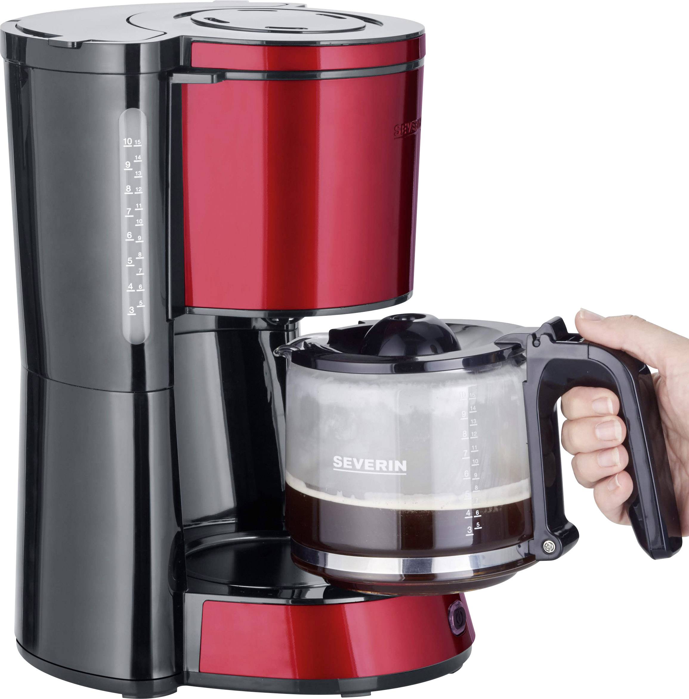 Een rode koffiemachine met zwarte accenten; een hand houdt een glazen kan met vers gezette koffie vast.