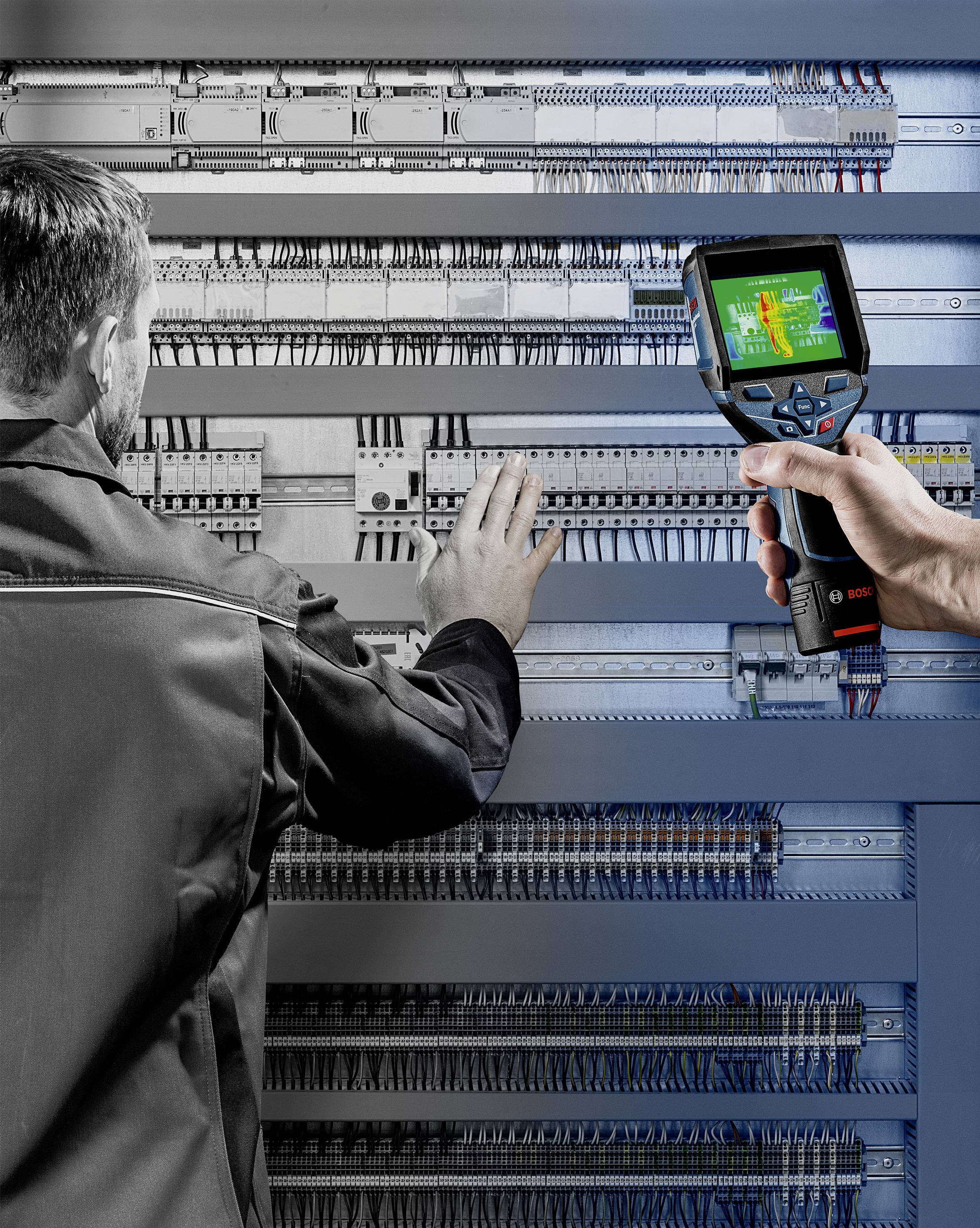 Een technicus inspecteert een schakelkast met behulp van een warmtebeeldcamera. Het display toont temperatuurverschillen.