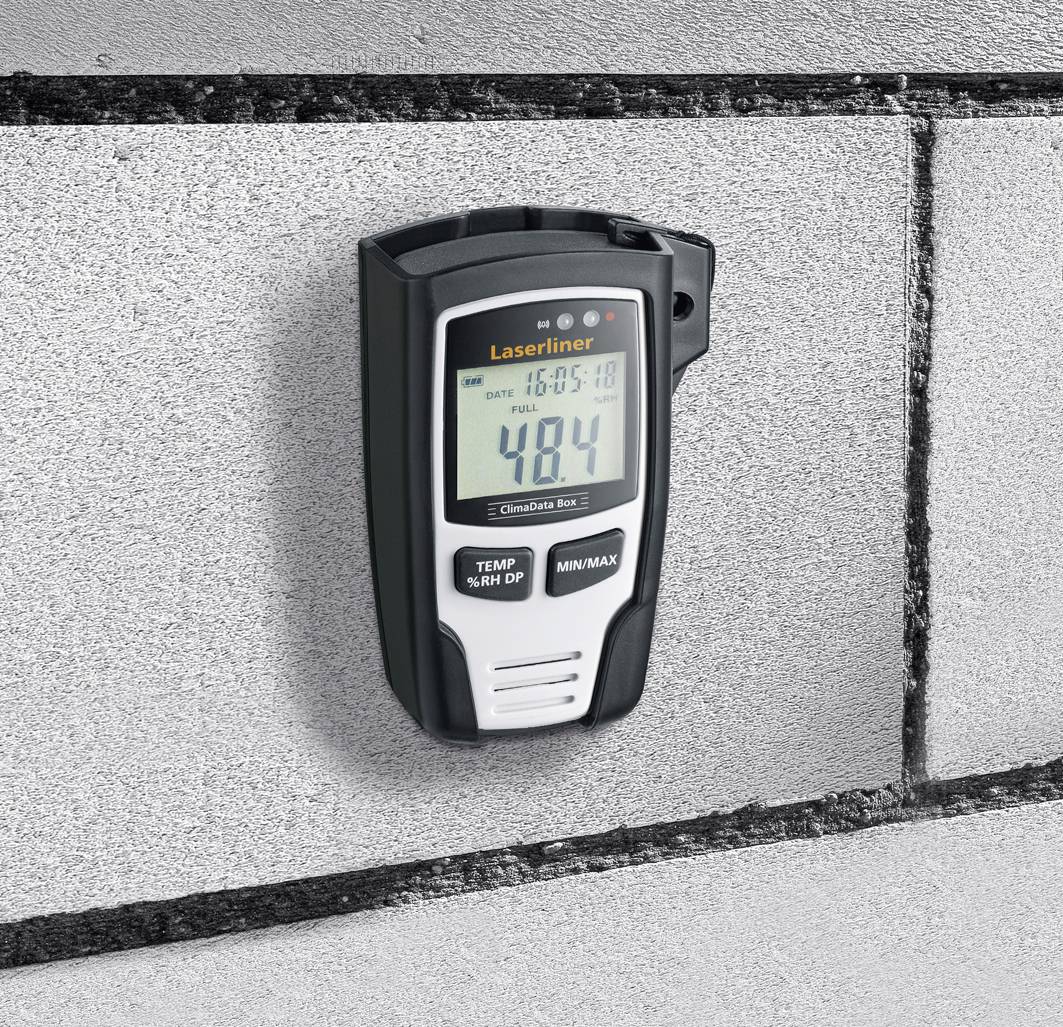 Een digitaal meetinstrument hangt aan een betonnen muur en toont temperatuur- en vochtwaarden. Het display geeft '48,4' weer.