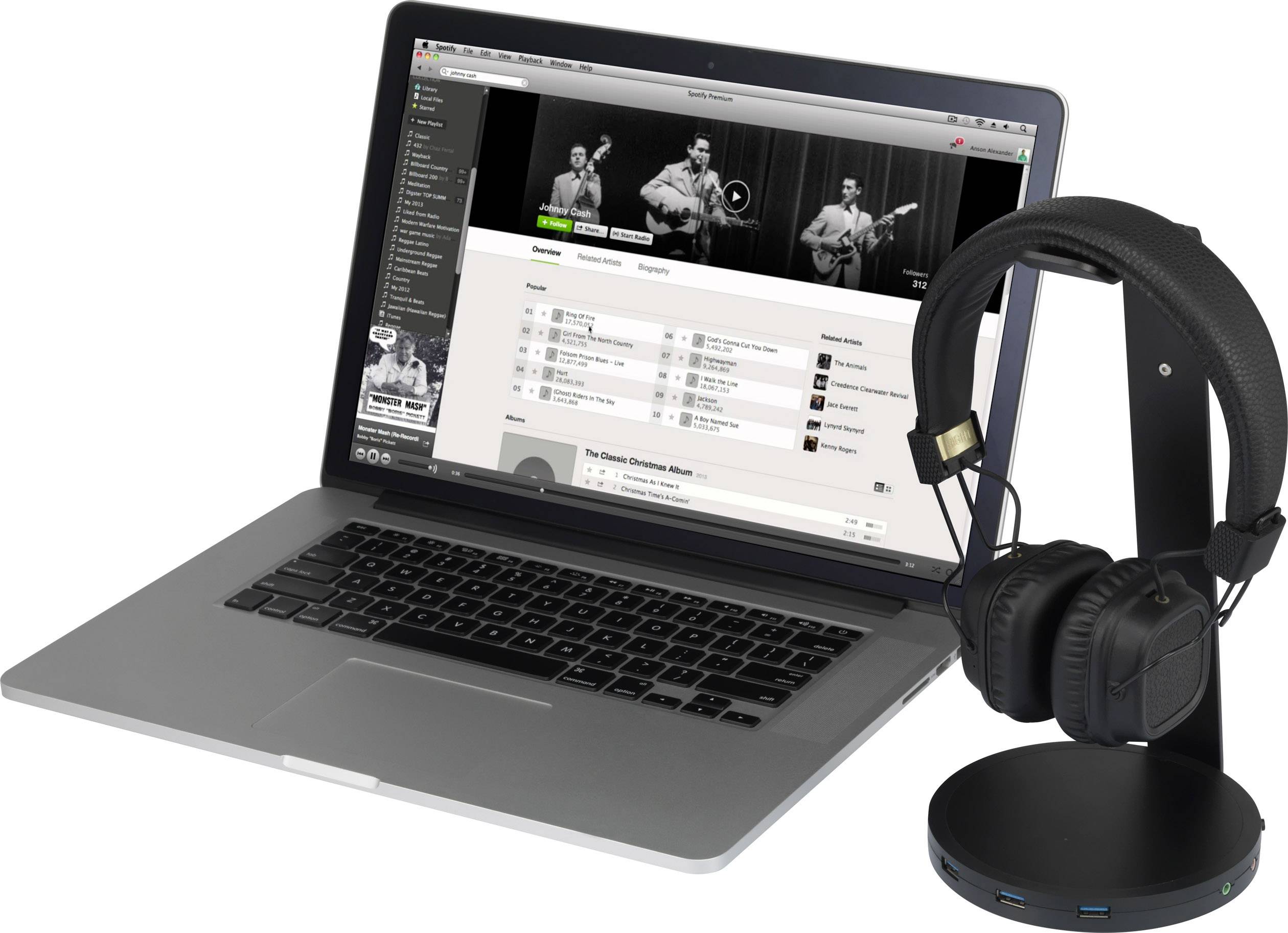 Een laptop met een geopende muziek-streamingdienst waarop een afspeellijst wordt weergegeven. Ernaast een zwarte koptelefoon op een standaard.