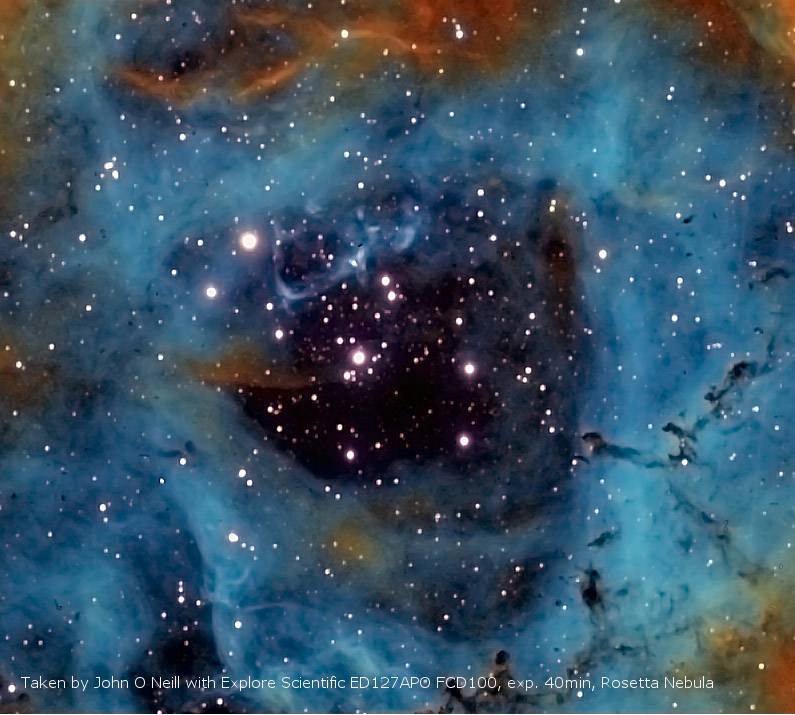 Een kleurrijk ruimteplaatje toont de Rosettenevel met lichtende blauwe en oranje gaswolken en talrijke fonkelende sterren op de achtergrond.