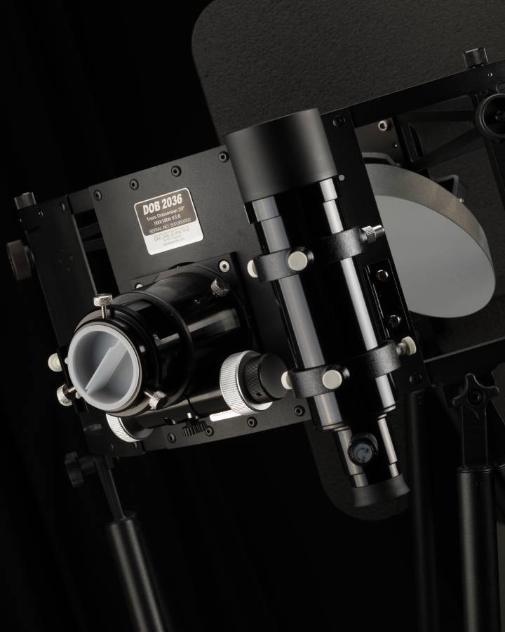 Een metalen optisch apparaat met lenzen en stelvoorzieningen, gemonteerd op een standaard. Het lijkt een wetenschappelijk instrument te zijn.