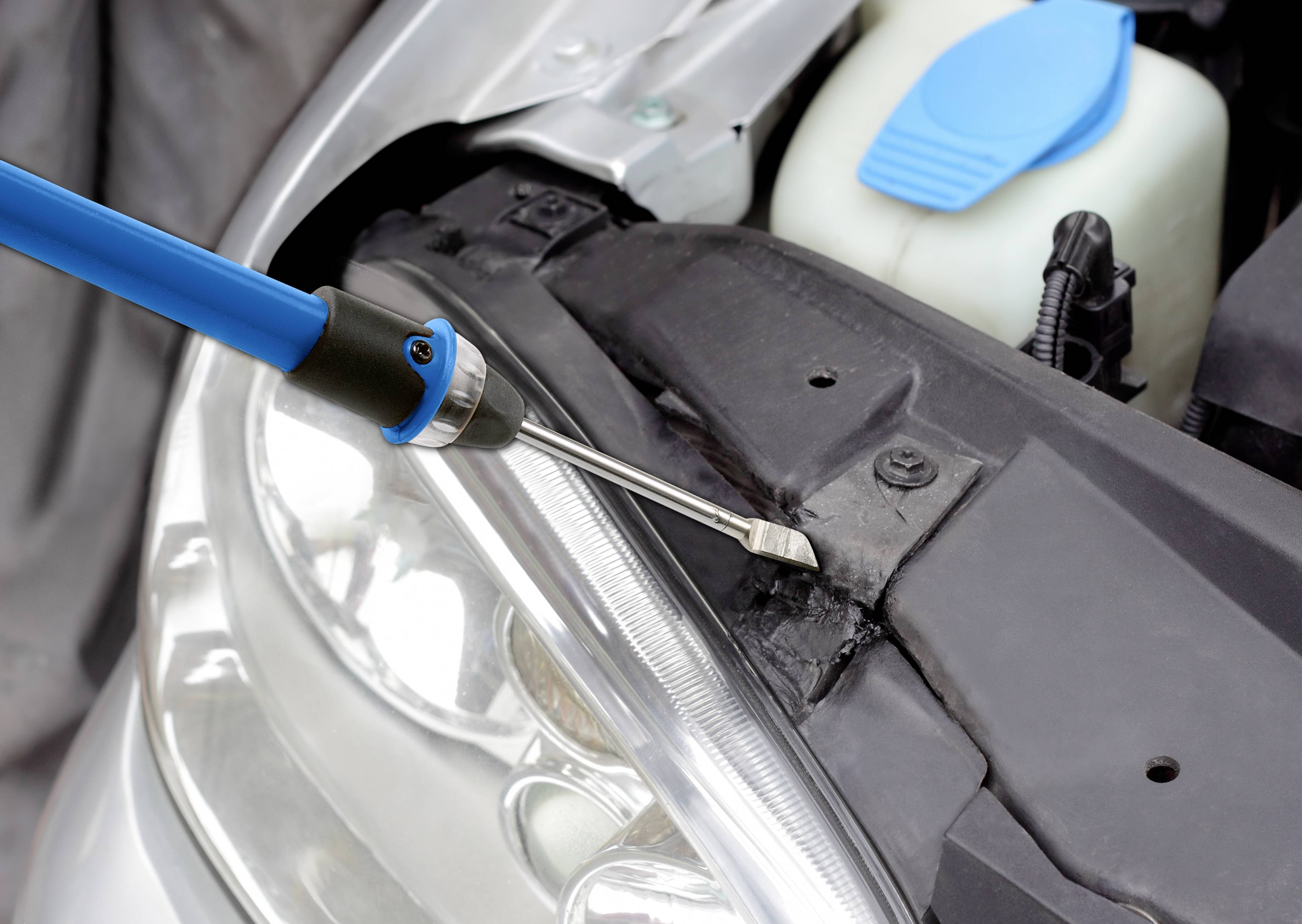 Een persoon monteert koplampen aan een auto met een schroevendraaier. Close-up toont het bovenste deel van de auto.