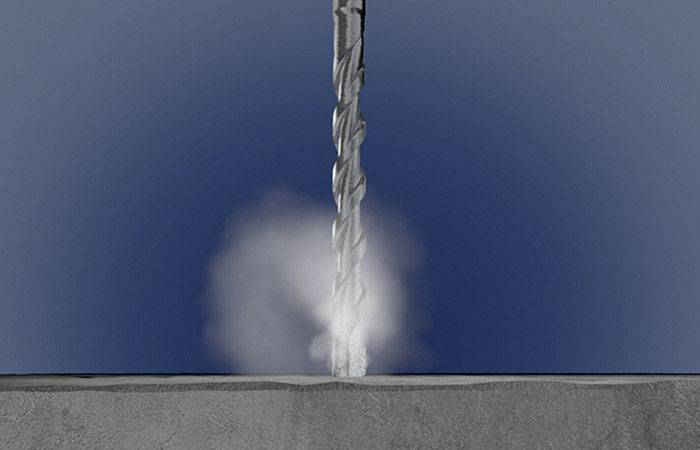 Een boormachine dringt door in beton, veroorzaakt stofwolken. De achtergrond is blauw.