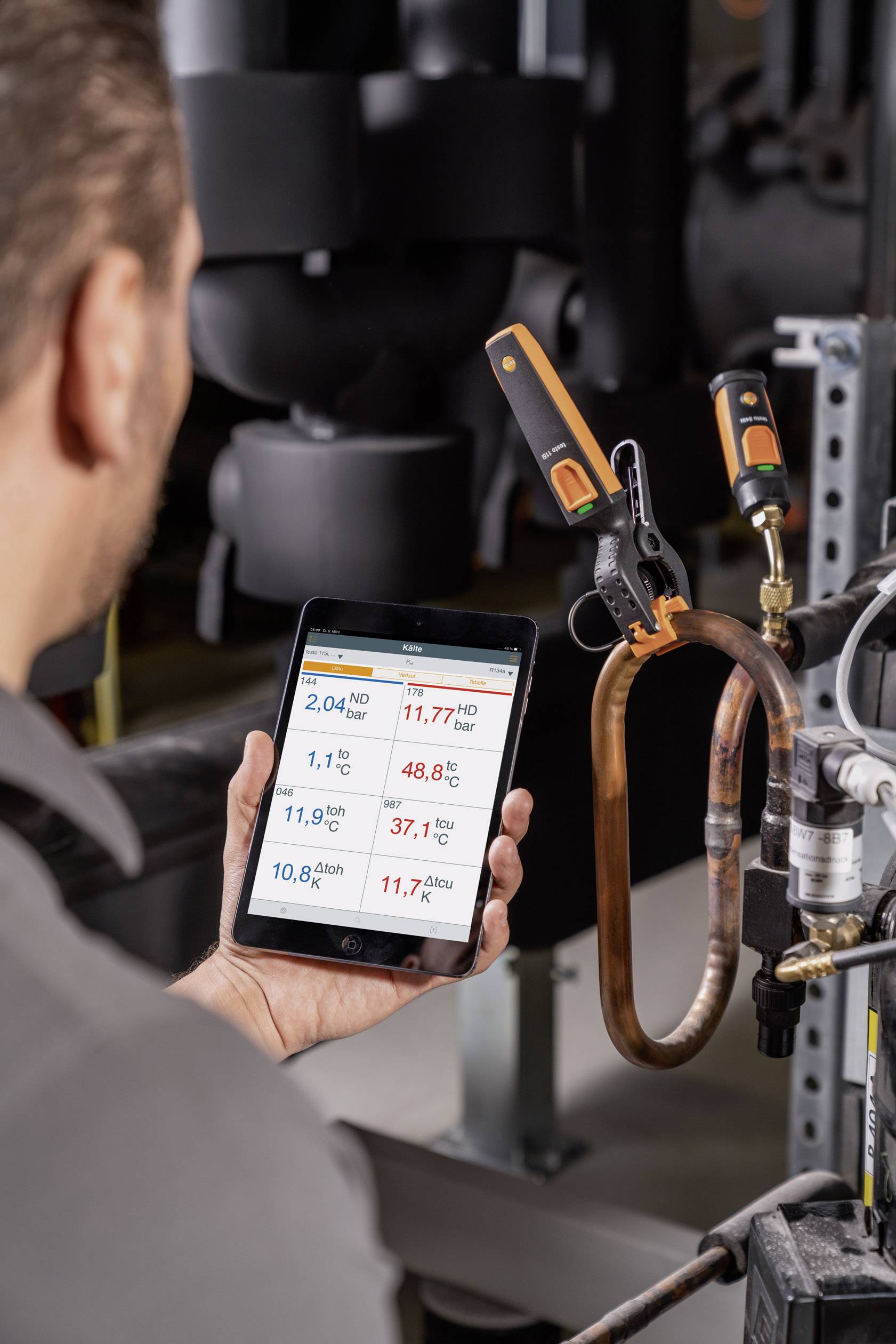 Een technicus controleert technische gegevens op een tablet tijdens onderhoudswerken aan een industriële installatie in een machineruimte.