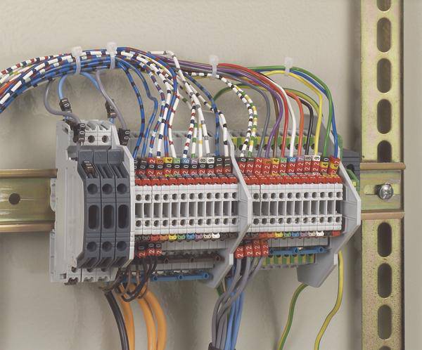Bedrade elektrische kast met verschillende gekleurde kabels en aansluitklemmen, gemonteerd op een metalen rail aan de muur.