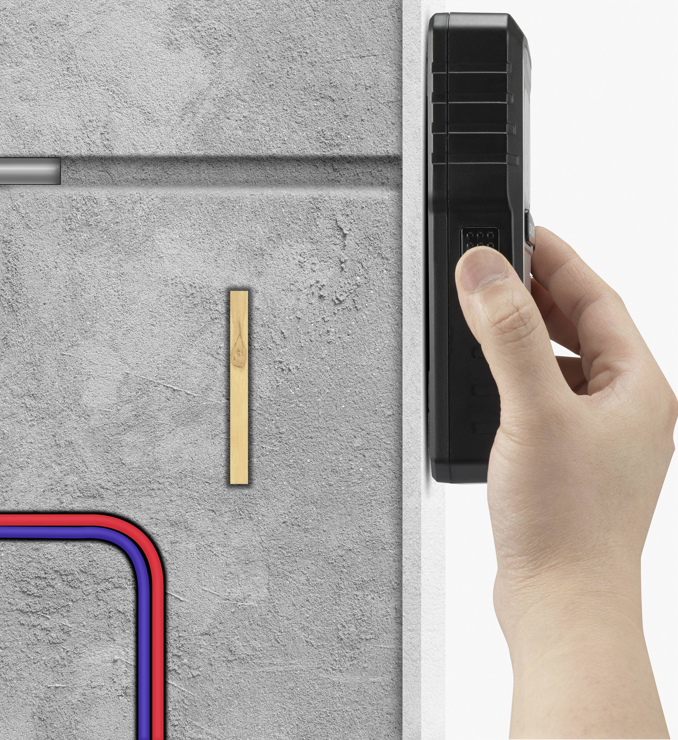 Een hand houdt een apparaat vast tegen een betonnen muur, naast waar gekleurde kabels en een houten lat liggen.