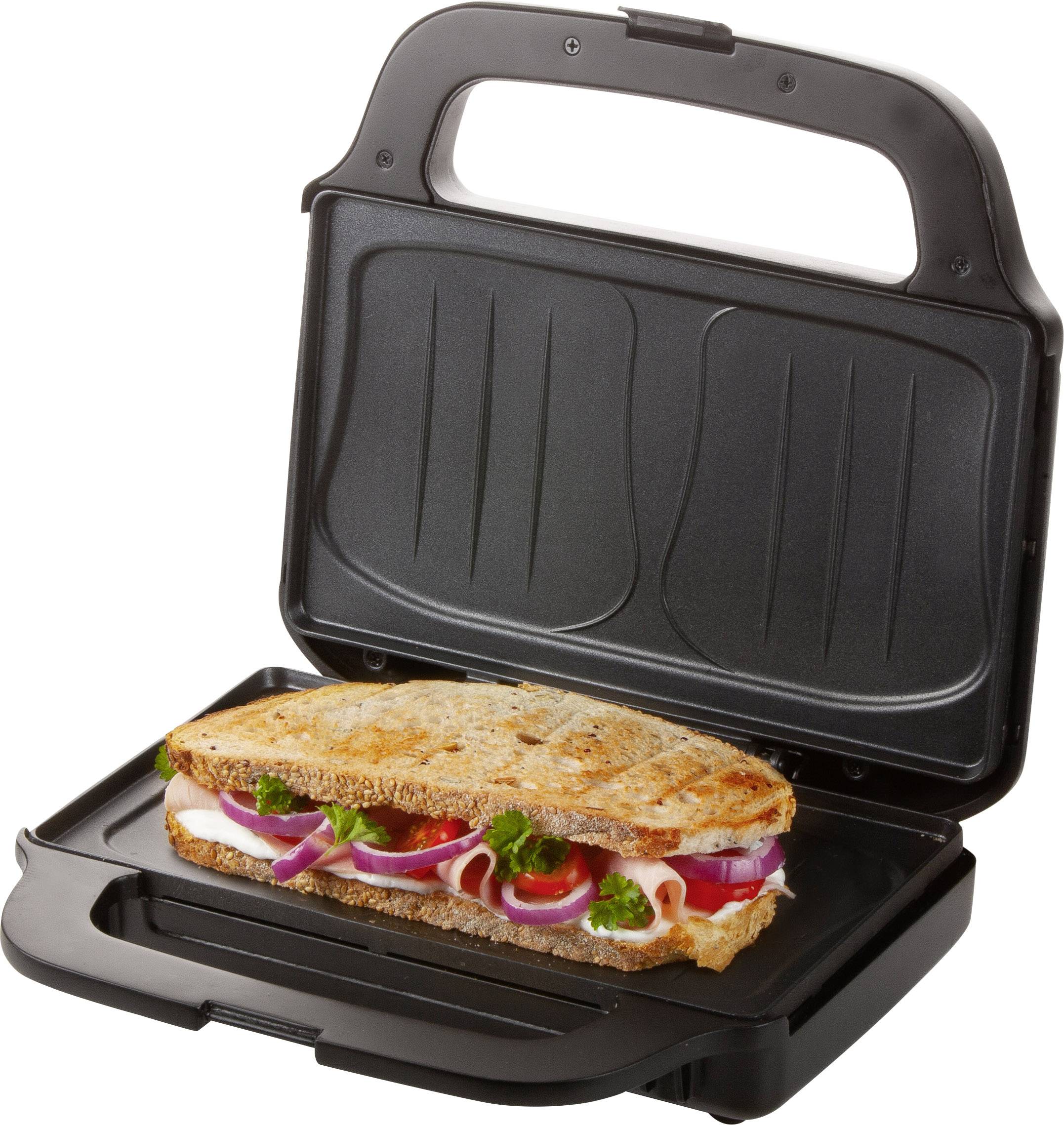 Een panini-sandwich met ham, tomaten, rode uien en peterselie ligt in een open tosti-ijzer.