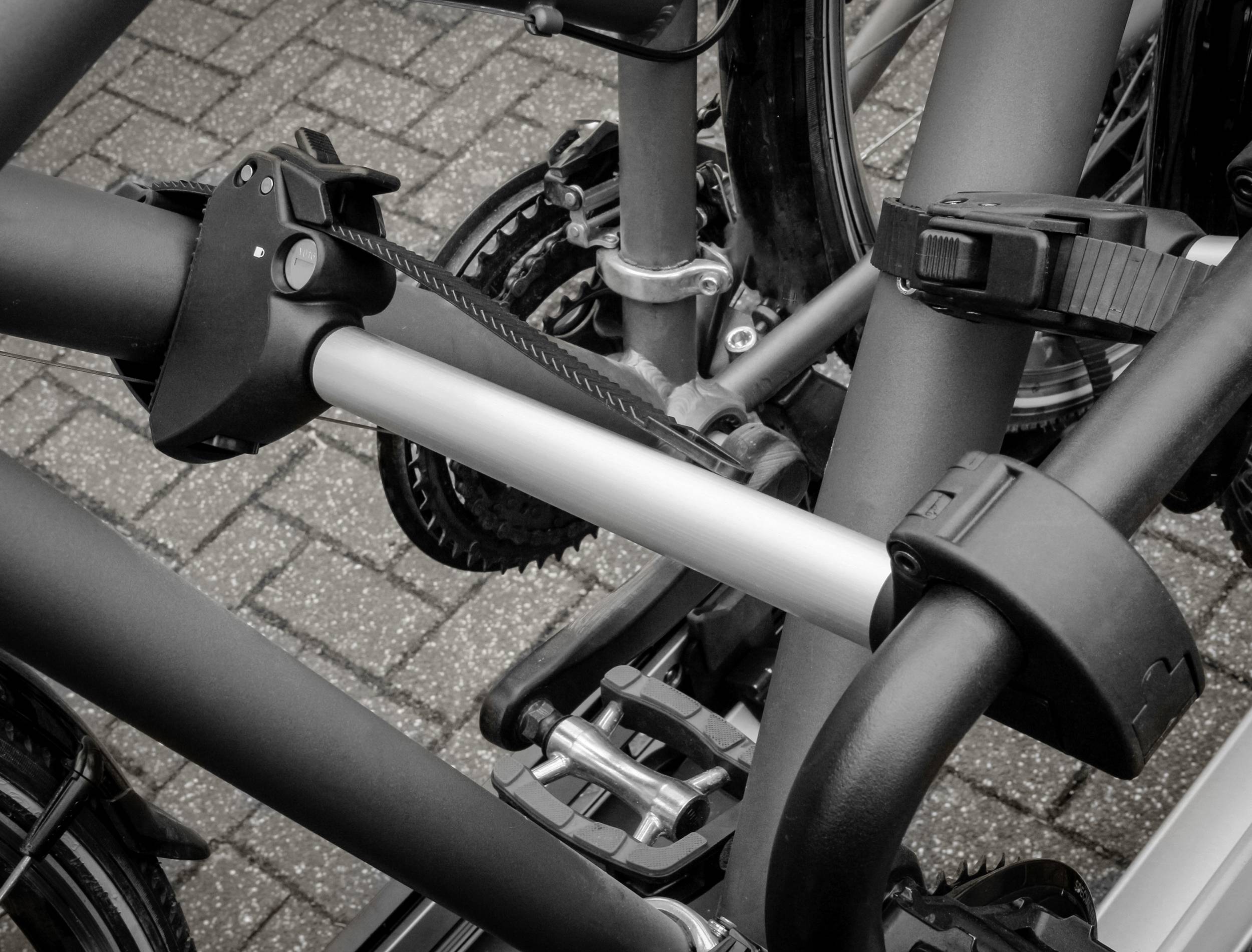 Zicht op meerdere fietsen die zijn vastgemaakt aan een moderne fietsenstalling. Focus op bevestigingen en wielen in zwart-wit.