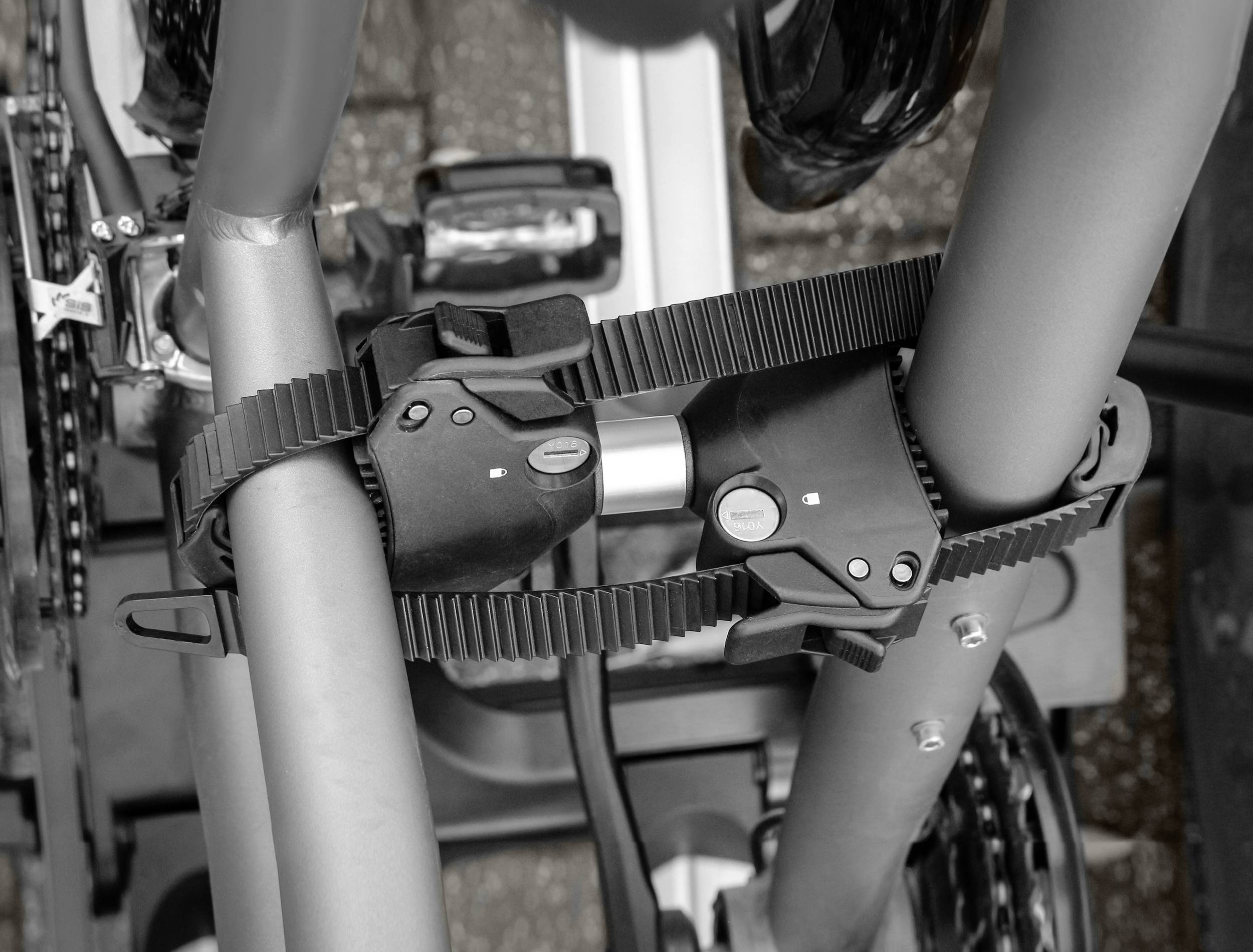 Fietsframe bevestigd op een fietsendrager, beveiligd met riemen en sloten ter voorkoming van diefstal.