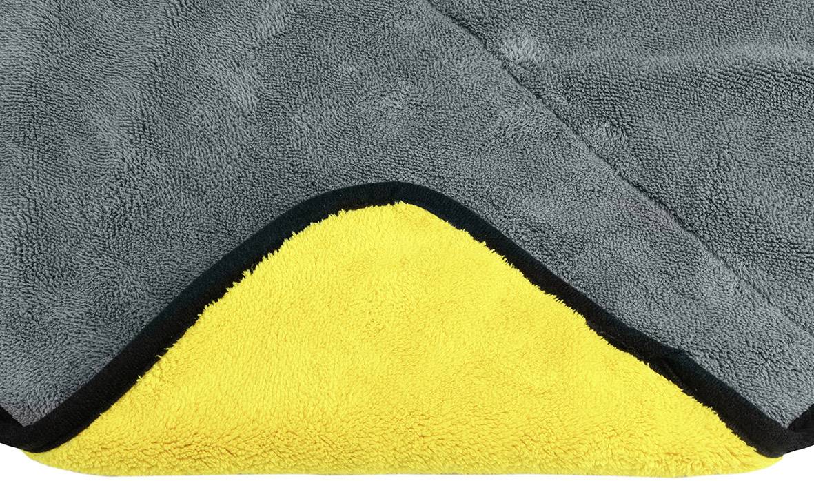 Grijze handdoek van zacht materiaal, met een omgeslagen hoek die een gele binnenkant onthult.