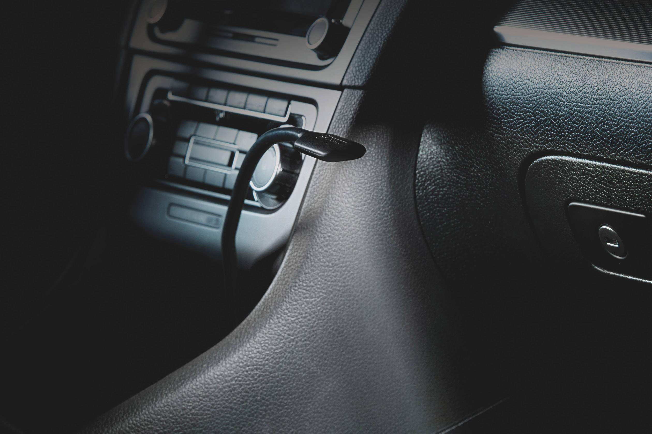 Interieur van een auto toont versnellingspook en dashboard. De focus ligt op de voertuiginstrumenten en bedieningselementen.