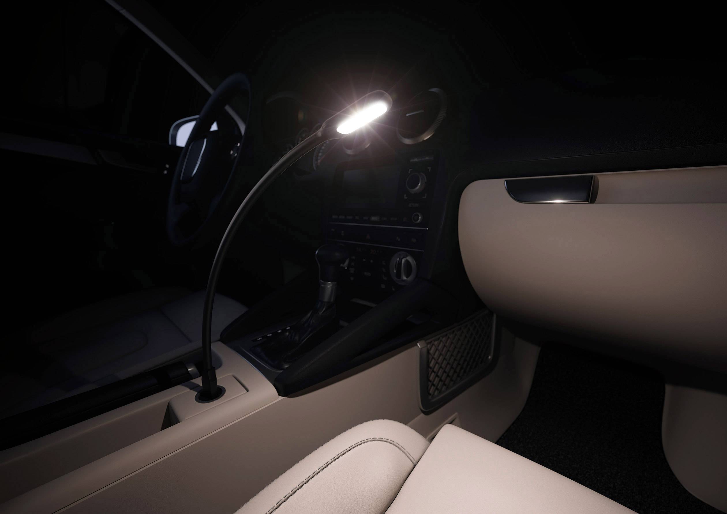 Een auto-interieur bij nacht. Een flexibele leeslamp verlicht het voorste gedeelte van het voertuig zacht.