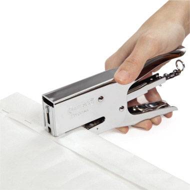 Een hand gebruikt een handnieter om een papier te nieten.