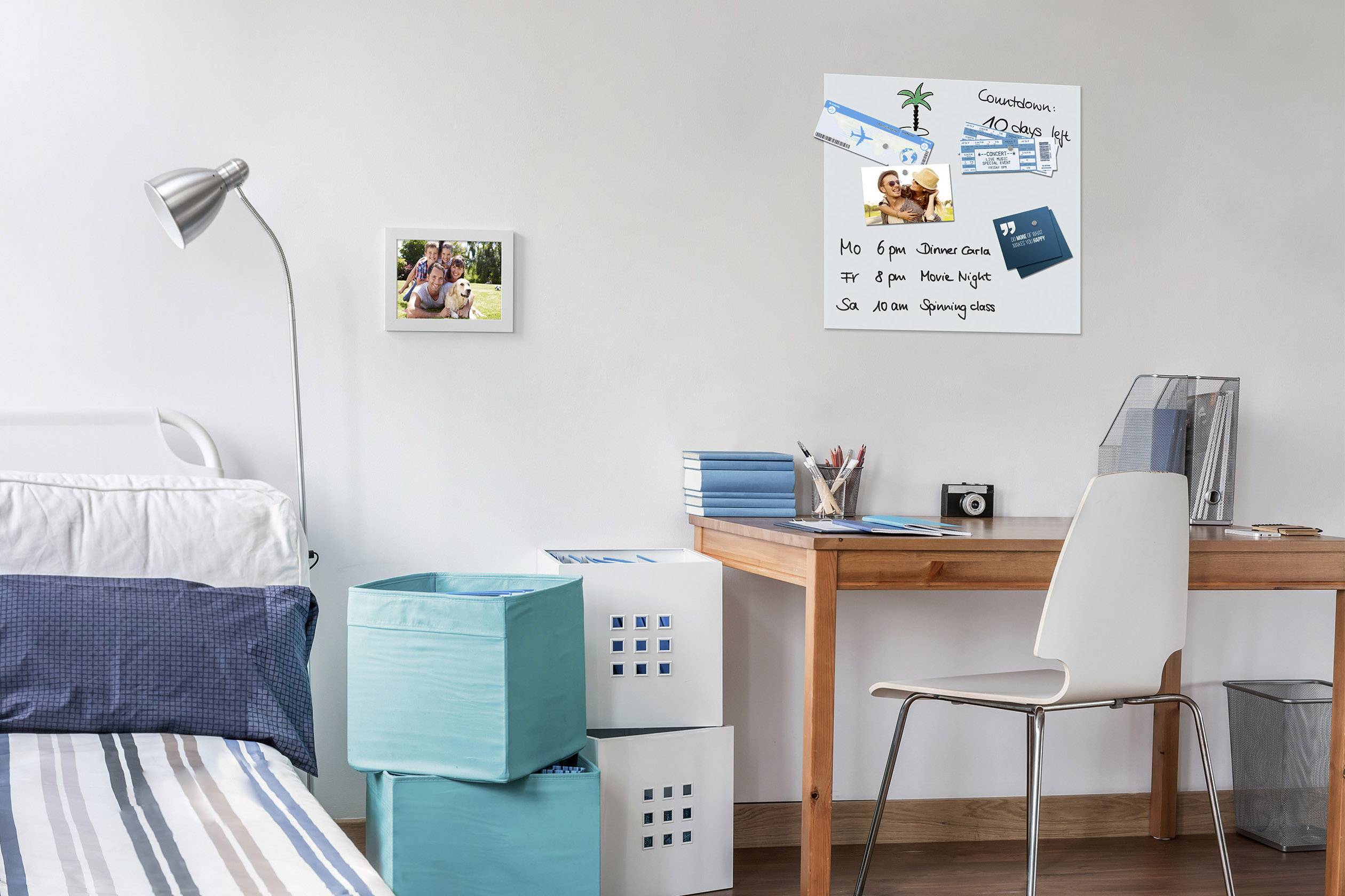 Een modern ingericht slaapkamer met een bed en een bureau. Aan de muur hangen foto's en een decoratief bord.