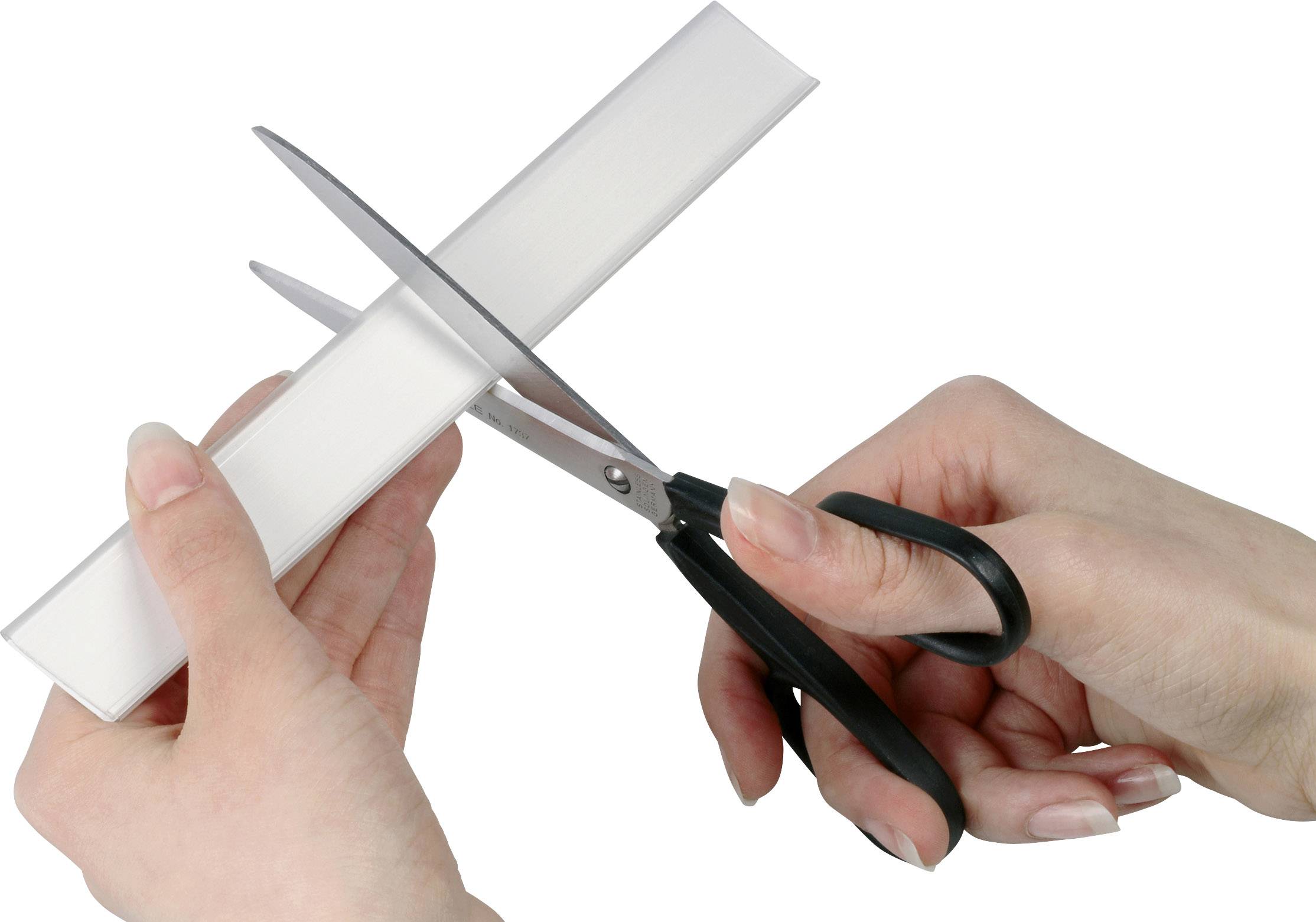 Twee handen knippen een wit vel papier met een schaar.