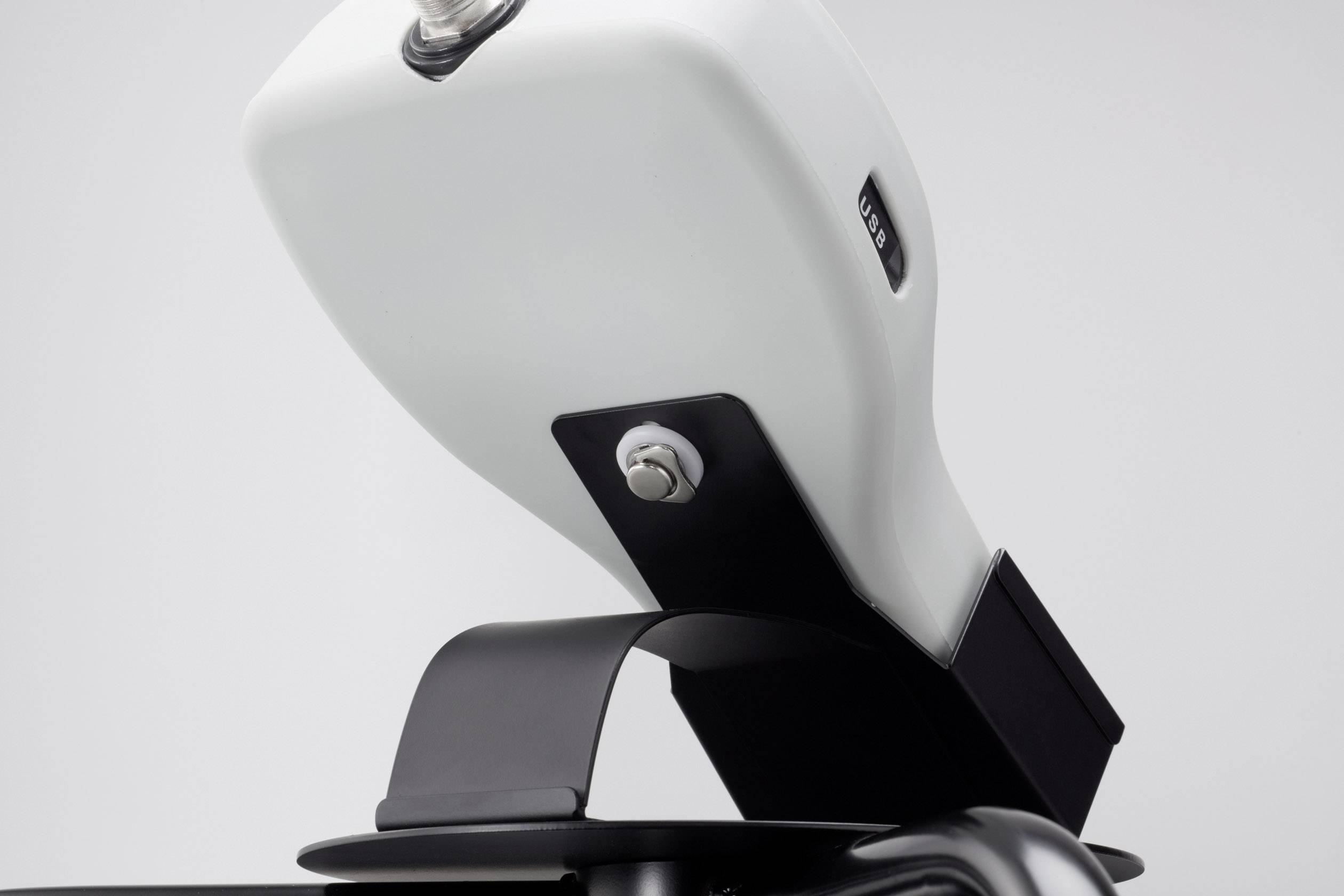 Een schijnwerper met een modern design, gemonteerd op een zwarte houder. Het witte lichaam heeft een ovale vorm met een metalen schakelaar.