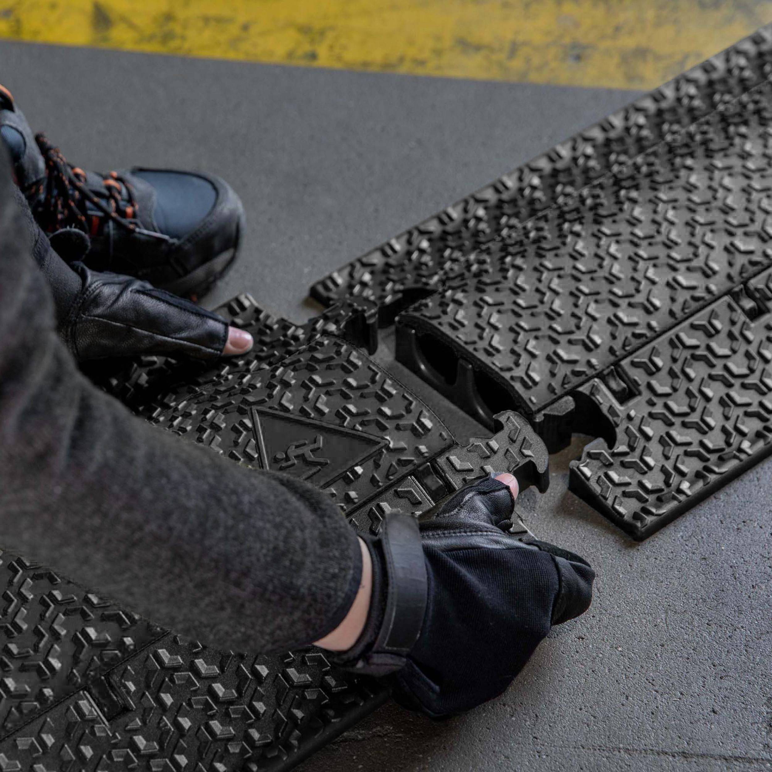 'Een persoon repareert een straatkabelgoot met rubberen handschoenen.'