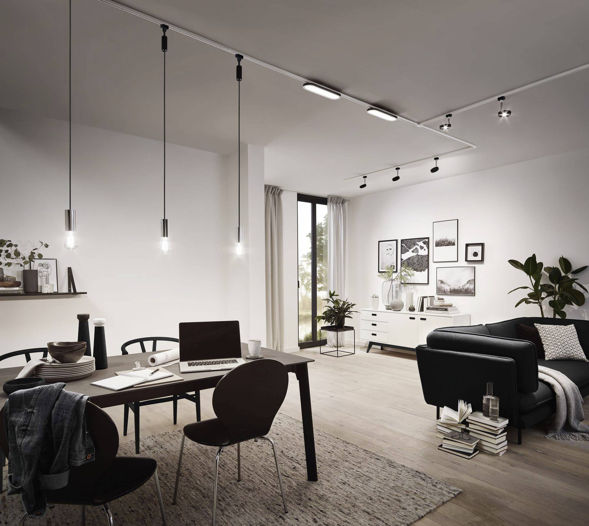 Een stijlvol ingericht woonkamer met eettafel; moderne verlichting, bank, schilderijen aan de muur, grote ramen en planten.