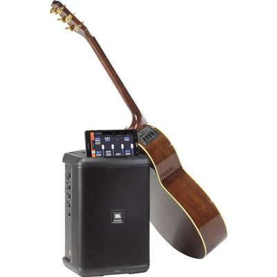 Een akoestische gitaar leunt tegen een luidspreker. Een smartphone is op de luidspreker geplaatst en toont een muziek-app.