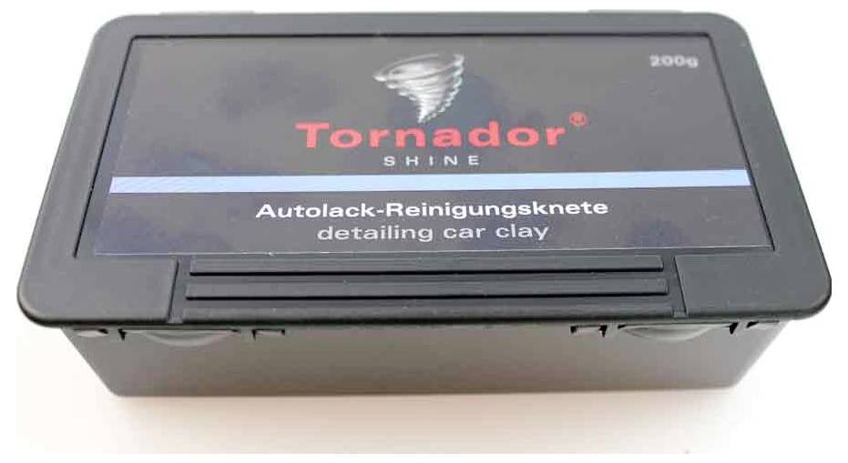 Zwarte rechthoekige container met het label Tornador Shine detailing auto clay, 200g. Blauwe streep met Duitse tekst: Autolack-Reinigingsknete.